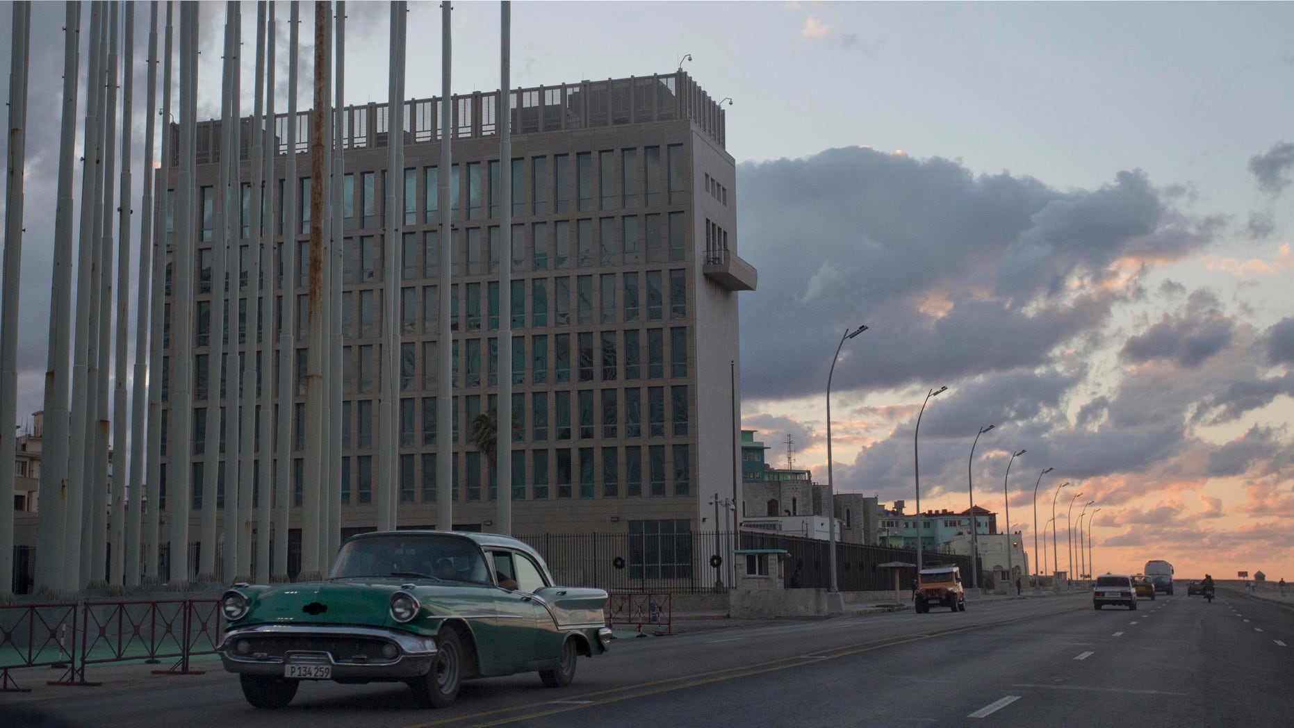 FILE - This Dec. 17, 2014 file photo shows a classic American car driving past the U.S. Interests Section buidling in Havana, Cuba. A half-century after Washington severed relations with Cuba, the seven-story mission is set to become a full-fledged embassy. The U.S. and Cuba announced on Dec. 17, 2014 they are re-establishing full diplomatic relations. (AP Photo/Desmond Boylan, File)