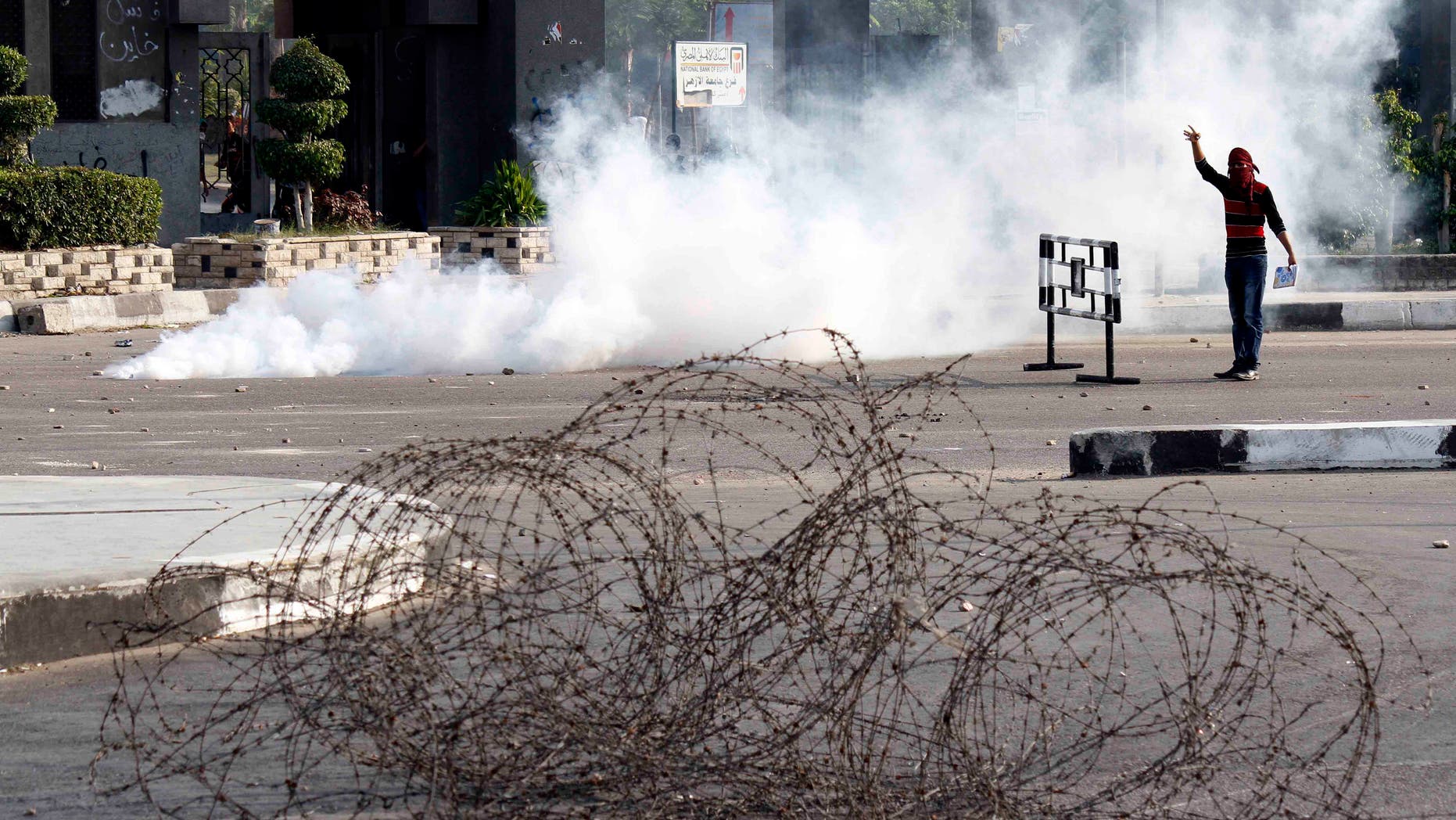 A masked protester stands in a cloud of tear gas during clashes with security forces dispersing several hundred pro- ousted President Mohammed Morsi university students who were rallying near Rabaah el-Adawiya, in eastern Cairo, Egypt, Monday, Oct. 28, 2013. As the protest got underway, army troops and police backed by armored vehicles blocked off the road leading to the site, creating a tense stand-off that lasted hours. By late afternoon, the students retreated to their campus, while pelting security forces with rocks.(AP Photo/Said Hamdy)