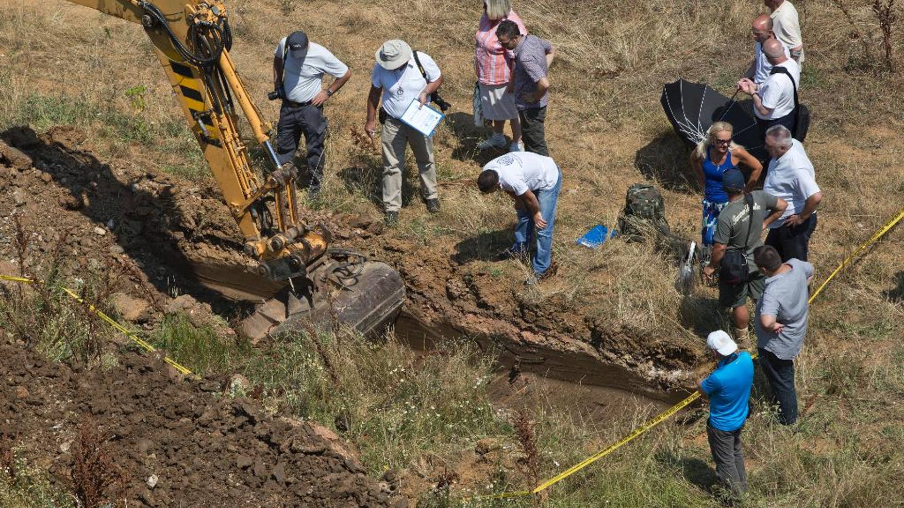 Yellow tape marks the site as an excavator digs a location that is being investigated at Pristina University campus following suspicions of a mass grave of people missing since the 1999 war, in Pristina on Wednesday, July 13, 2016. About 1,650 people remain missing since the end of the war with Serbia in 1999. (AP Photo/Visar Kryeziu)