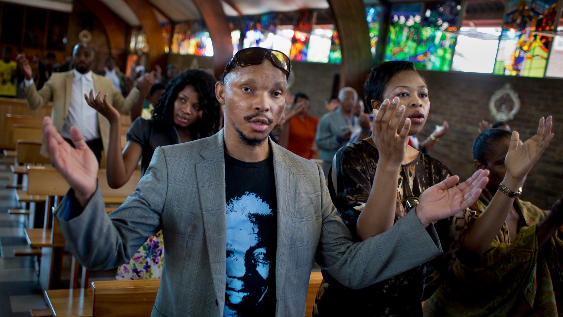 Mourners attend an early morning church service in memory of Nelson Mandela at the Regina Mundi church, which became one of the focal points of the anti-apartheid struggle, in Soweto, Johannesburg, People in South Africa are taking part in a day of "prayer and reflection" for late President Nelson Mandela. (AP Photo/Ben Curtis)