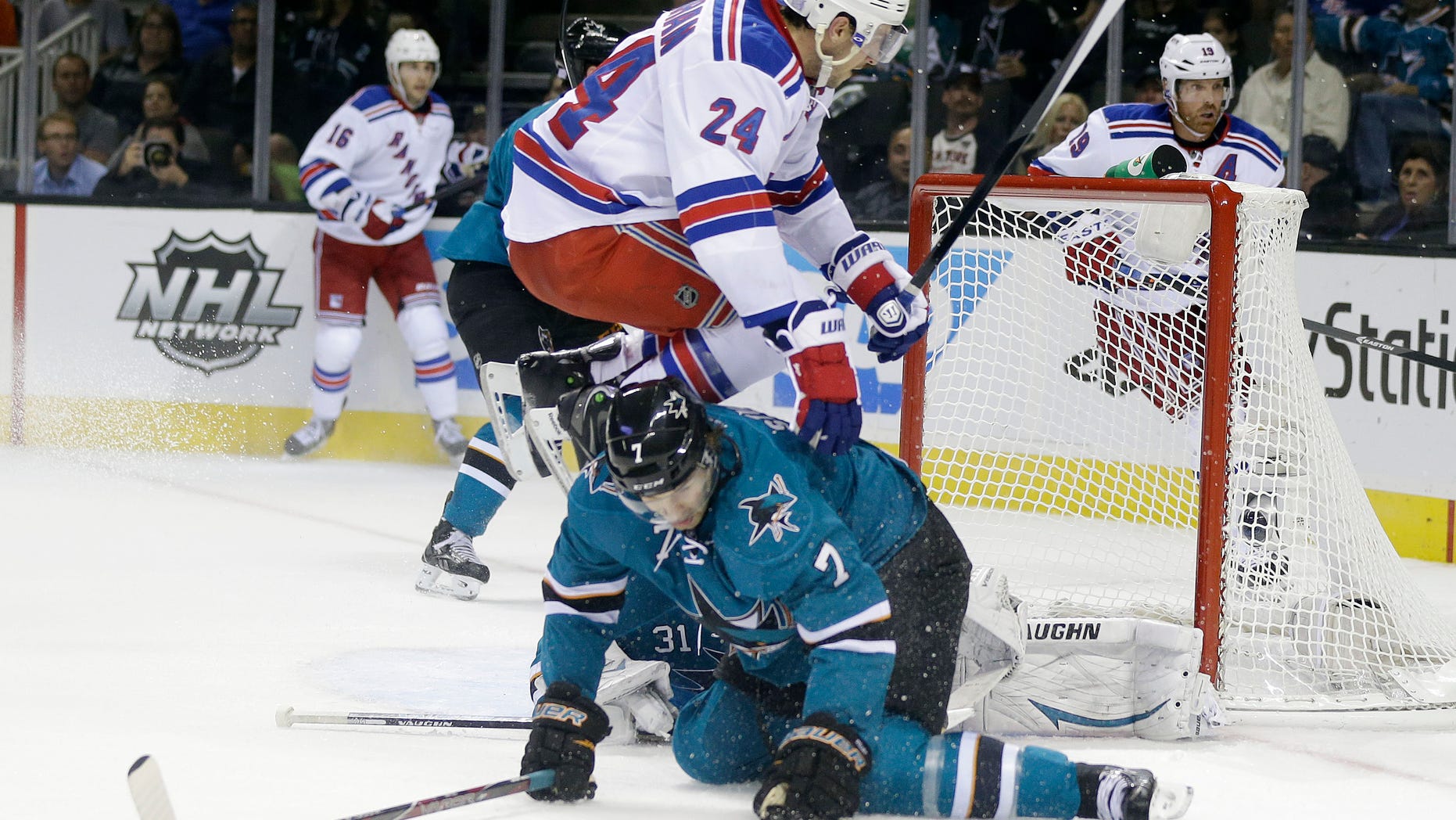 New York Rangers' Ryan Callahan (24) jumps over San Jose Sharks' Brad Stuart (7) during the second period of an NHL hockey game on Tuesday, Oct. 8, 2013, in San Jose, Calif. (AP Photo/Marcio Jose Sanchez)