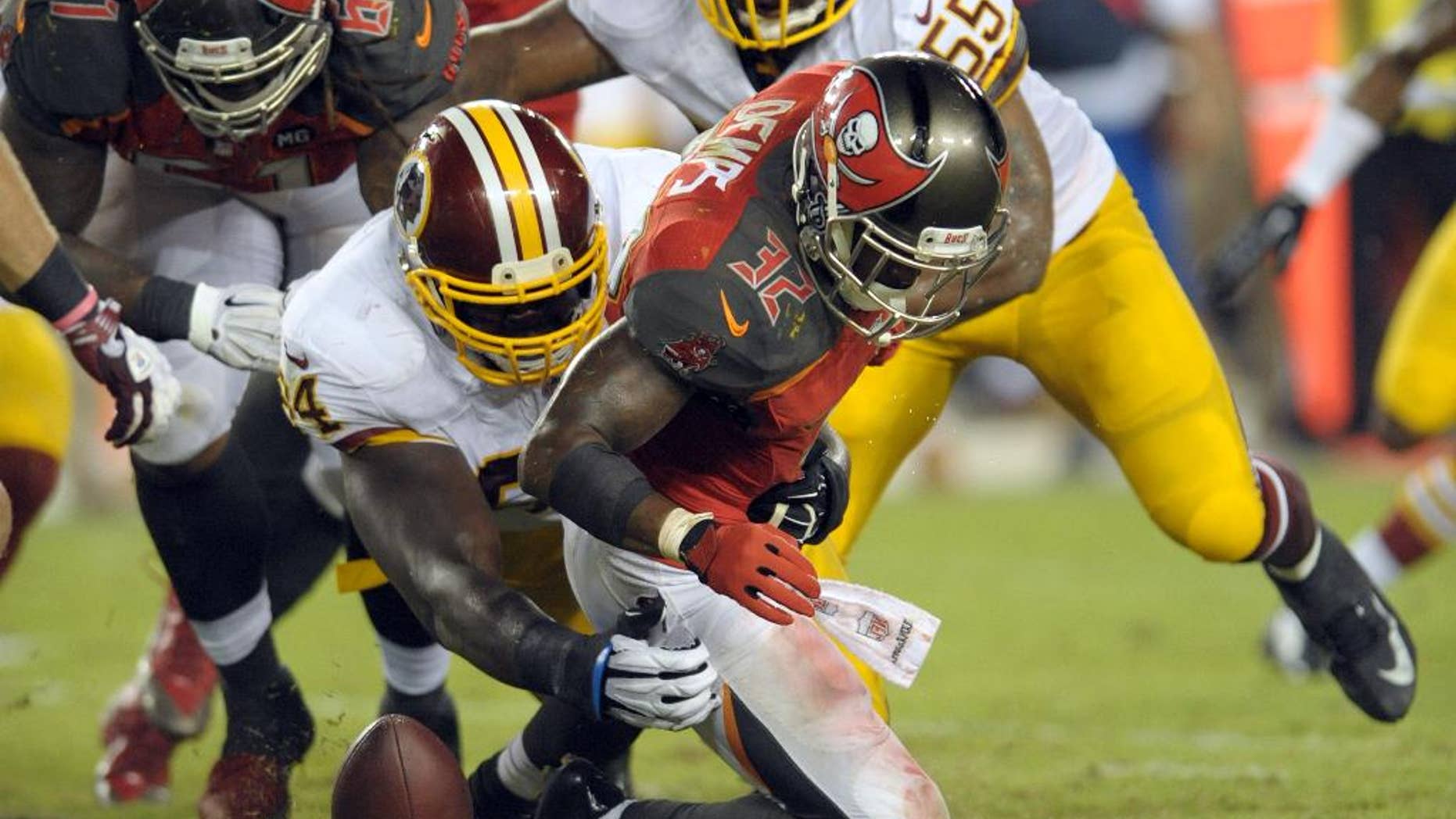 Tampa Bay Buccaneers running back Jeff Demps (32) fumbles the ball after being hit by Washington Redskins defensive tackle Clifton Geathers (94) during the fourth quarter of an NFL preseason football game Thursday, Aug. 28, 2014, in Tampa, Fla. The Buccaneers recovered the ball. (AP Photo/Steve Nesius)