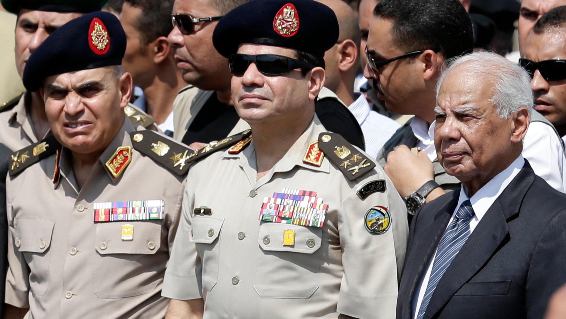 FILE - In this file photo taken Friday, Sept. 20, 2013, Egypt's Defense Minister Gen. Abdel-Fattah el-Sissi, center, Egyptian Prime Minister Hazem el-Beblawi, right, and army's Chief of Staff Lt. Gen. Sedki Sobhi, left, attend the funeral of Giza Police Gen. Nabil Farrag in Cairo, Egypt. A heavy crackdown has thrown the 85-year-old Brotherhood into an existential crisis. Once Egypt’s dominant political force, it is now reduced to keeping a campaign of street protest simmering to show it cannot be completely wiped out and must one day have a place again in the political system. (AP Photo/Hassan Ammar, File)