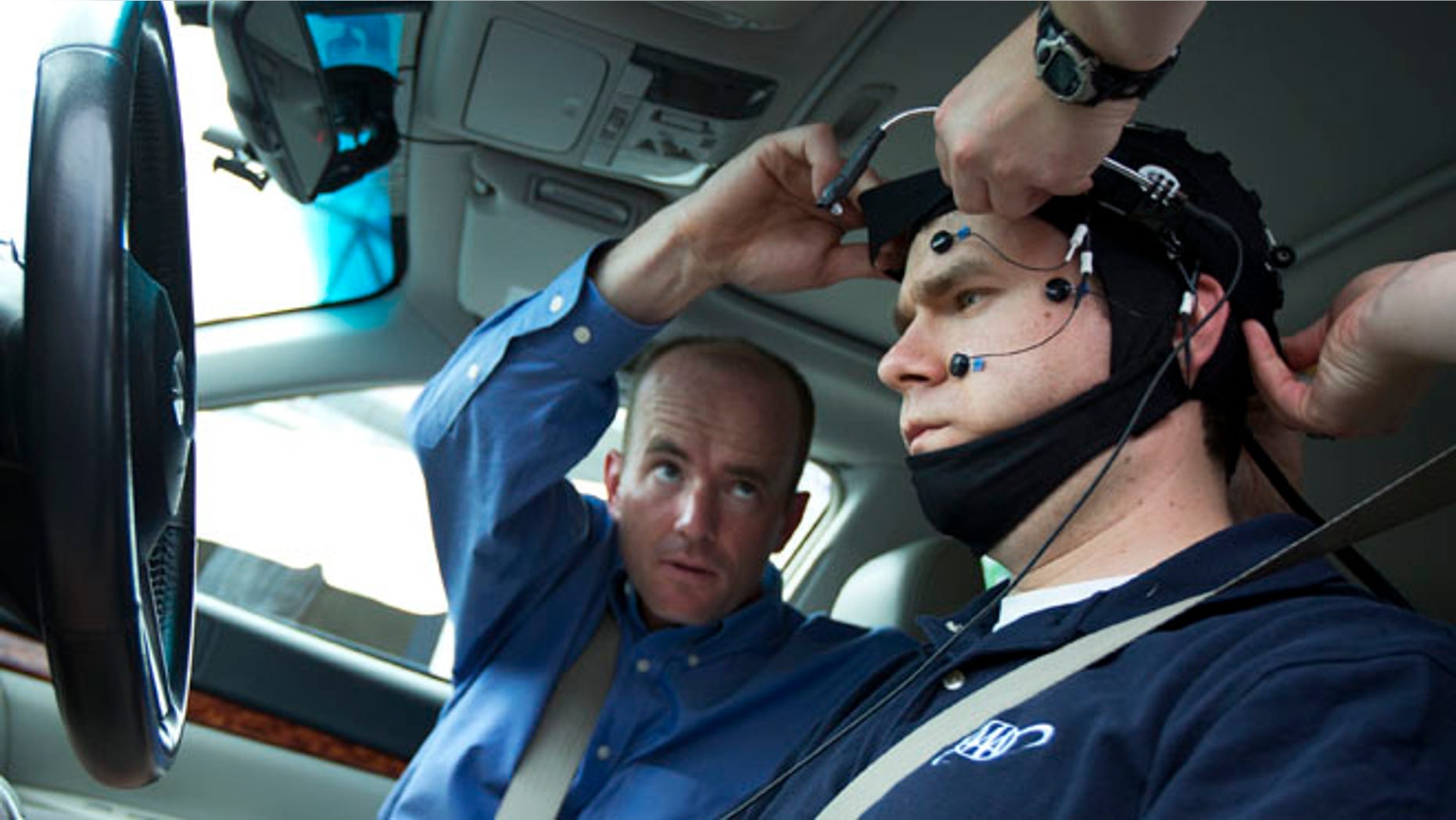 Russ Martin of triple A, is assisted by Joel Cooper, left, hooking the electroencephalographic (EEG)-configured skull cap to the research vehicle during a demonstrations in support of their new study on distracted driving in Landover, Md., Tuesday, June 11, 2013. (AP Photo/Manuel Balce Ceneta)