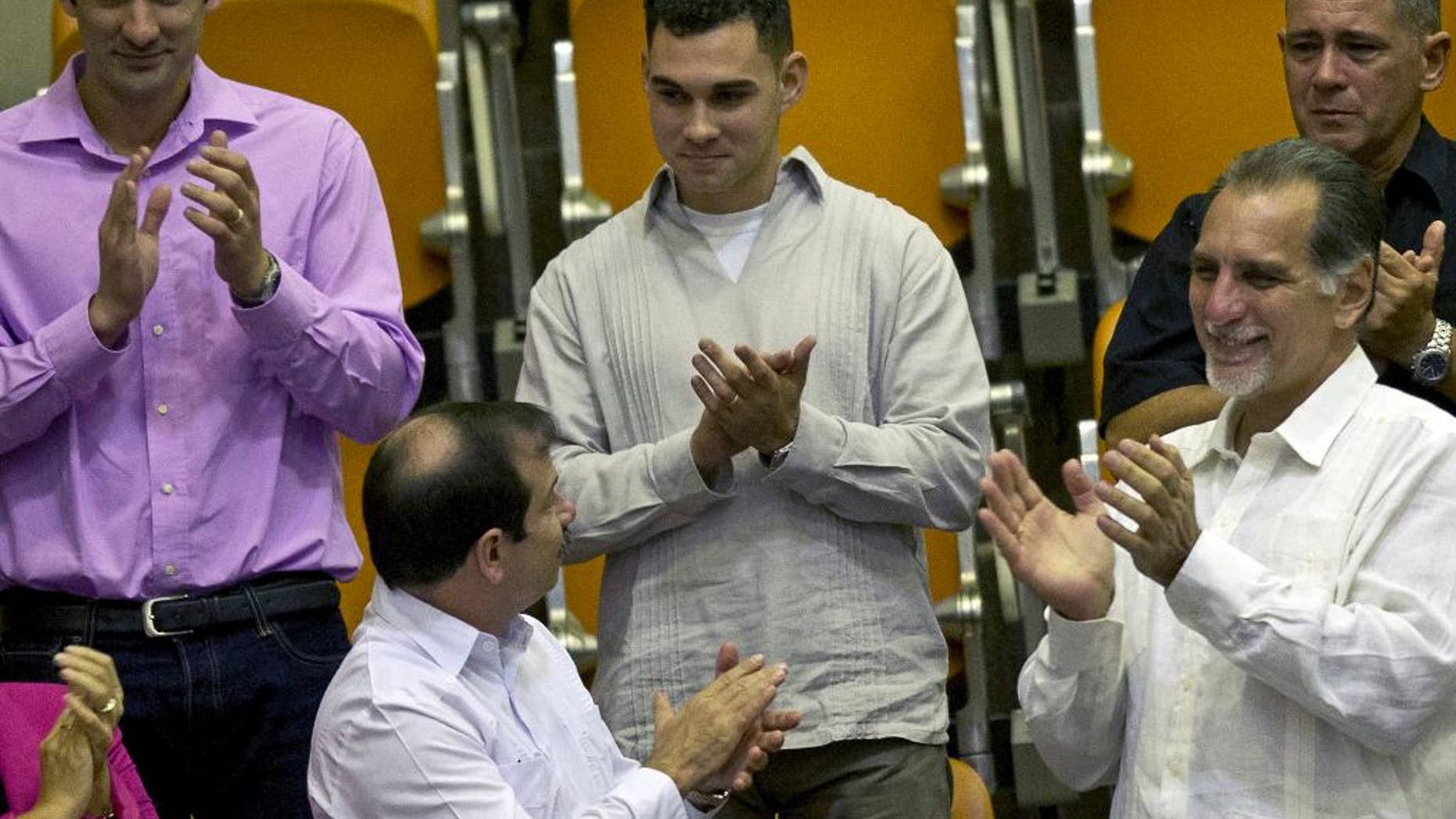 FILE - In this Dec. 20, 2014 file photo, Elian Gonzalez, center, the young Cuban rafter who was at the center of a bitter custody battle in 2000 between relatives in Miami and his father in Cuba, is recognized with applause during the legislative session at the National Assembly in Havana, Cuba. Cuban government website Cubadebate reported Friday, July 15, 2016, the now 22-year-old Gonzalez received his diploma in industrial engineering from the University of Matanzas. Flanked by Fernando Gonzalez, bottom left, and Rene Gonzalez, front right, members of the "Cuban Five" spy ring. (AP Photo/Ramon Espinosa)