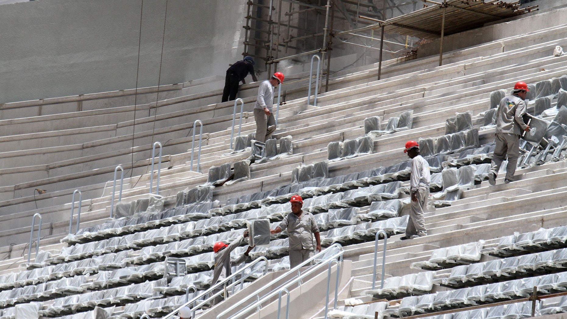 FILE - In this Jan. 21, 2014 file photo released by Portal da Copa, workers install seats at the Arena da Baixada stadium in Curitiba, Brazil. The southern city of Curitiba is expected to remain in the World Cup despite construction delays on its stadium, Brazilian Sports Minister Aldo Rebelo said Wednesday, Feb. 5, 2014. During a visit to the city, he expressed confidence that local organizers will be able to show FIFA that the stadium will be ready in time to hold its four matches scheduled for football's showcase event in June. (AP Photo/Portal da Copa, Paulino Menezes, File)