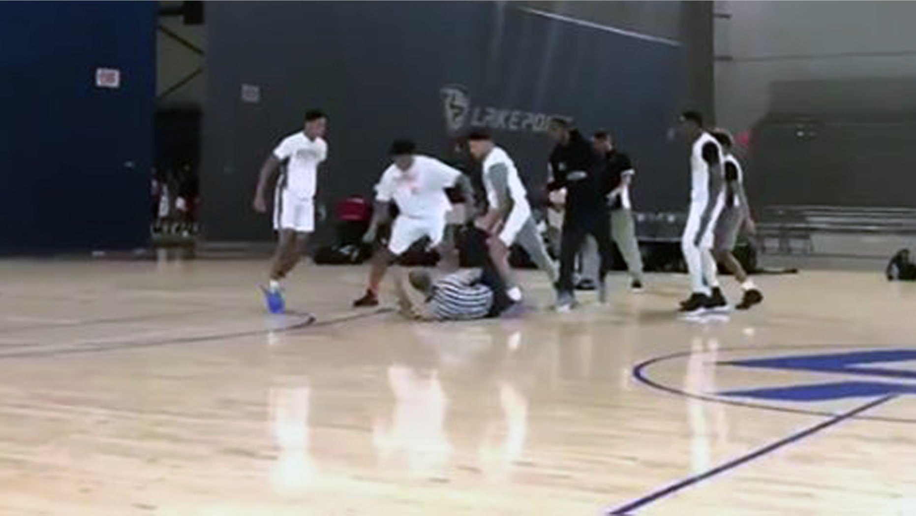 Players surrounded a fallen referee after a fight breaks out at an AAU game in Cartersville, Ga. Sunday