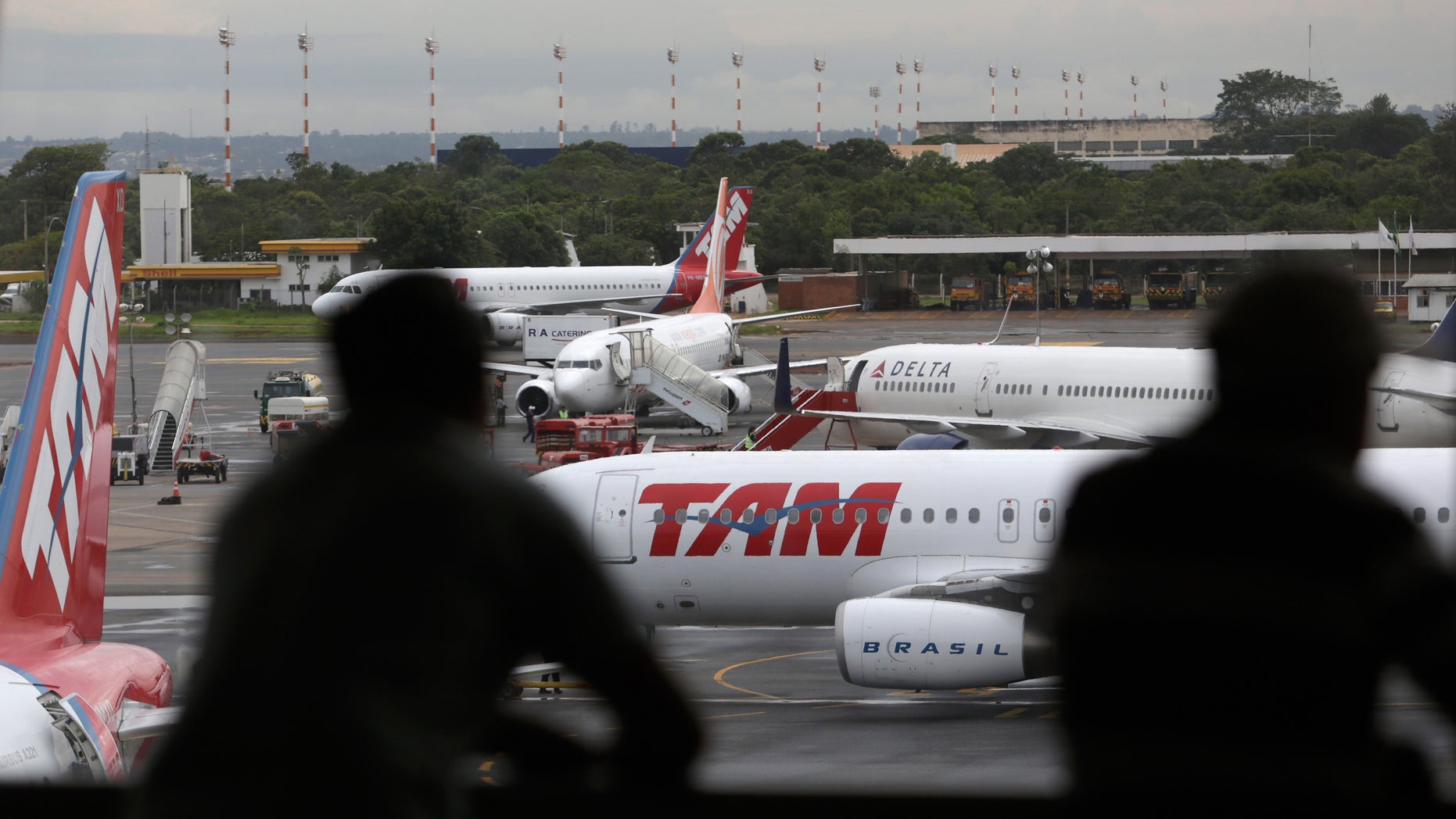 FILE - In this Nov. 28, 2013 file photo, people look at jetliners at the Brasilia international airport, in Brasilia, Brazil. As Brazil's airline industry has come under pressure from the national government to control fares, Avianca Brasil has joined Azul in becoming the second Brazilian airline to promise to cap prices for the upcoming football World Cup, which opens in June. (AP Photo/Eraldo Peres, File)