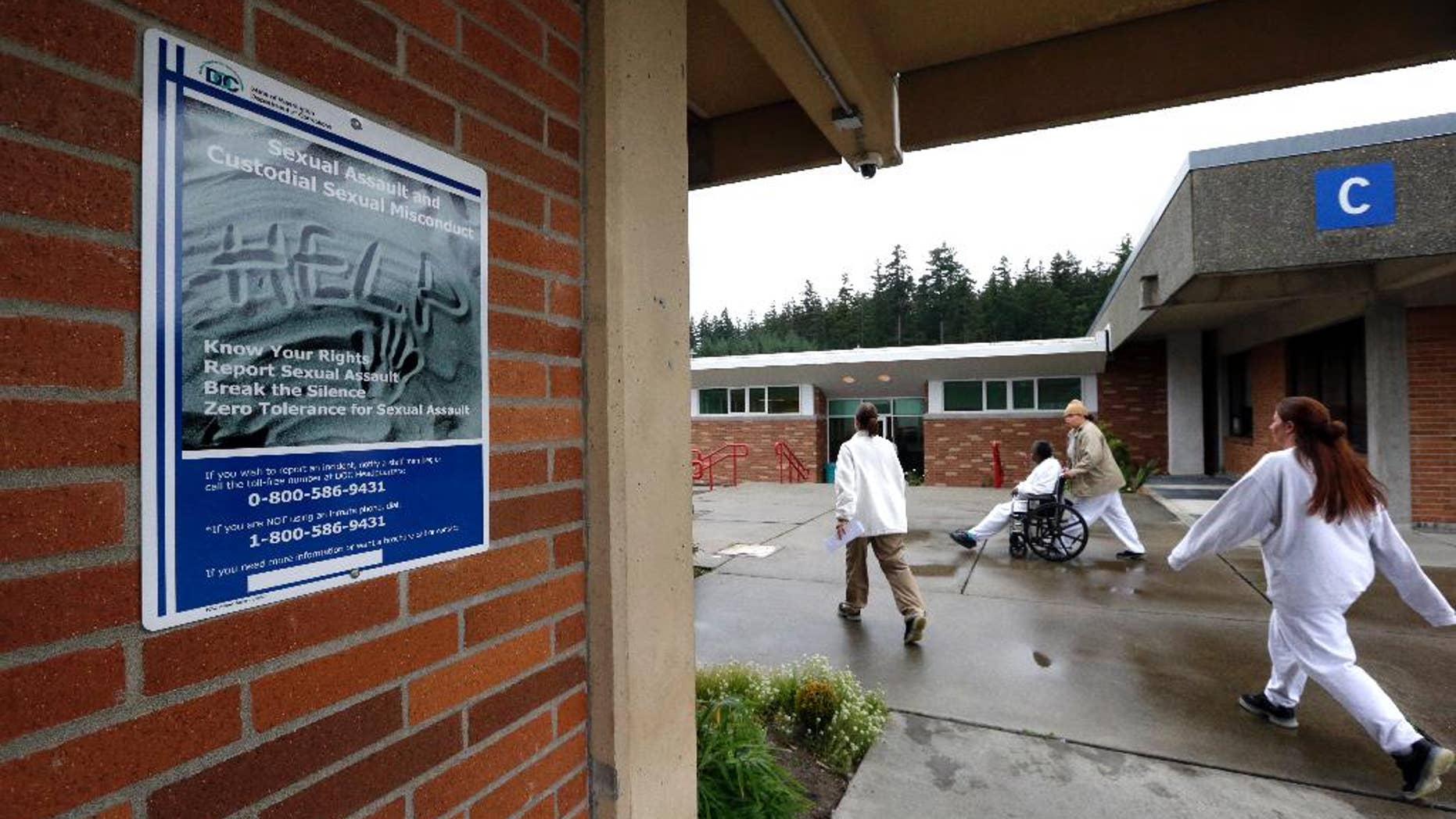 In this photo taken Oct. 17, 2014, offenders walk in view of a poster explaining how to help prevent or report sexual assault at the Washington Corrections Center For Women in Gig Harbor, Wash. A 2003 federal law was meant to put a stop to sexual assault in the nation’s prisons, jails and juvenile detention centers and more than $110 million in state and federal taxpayer money has been spent to help states tackle the problem. By last fall, every state was supposed to have dozens of new standards in place, ranging from increased training of staff about sex abuse policies to procedures meant to help inmates safely report attacks. (AP Photo/Elaine Thompson)