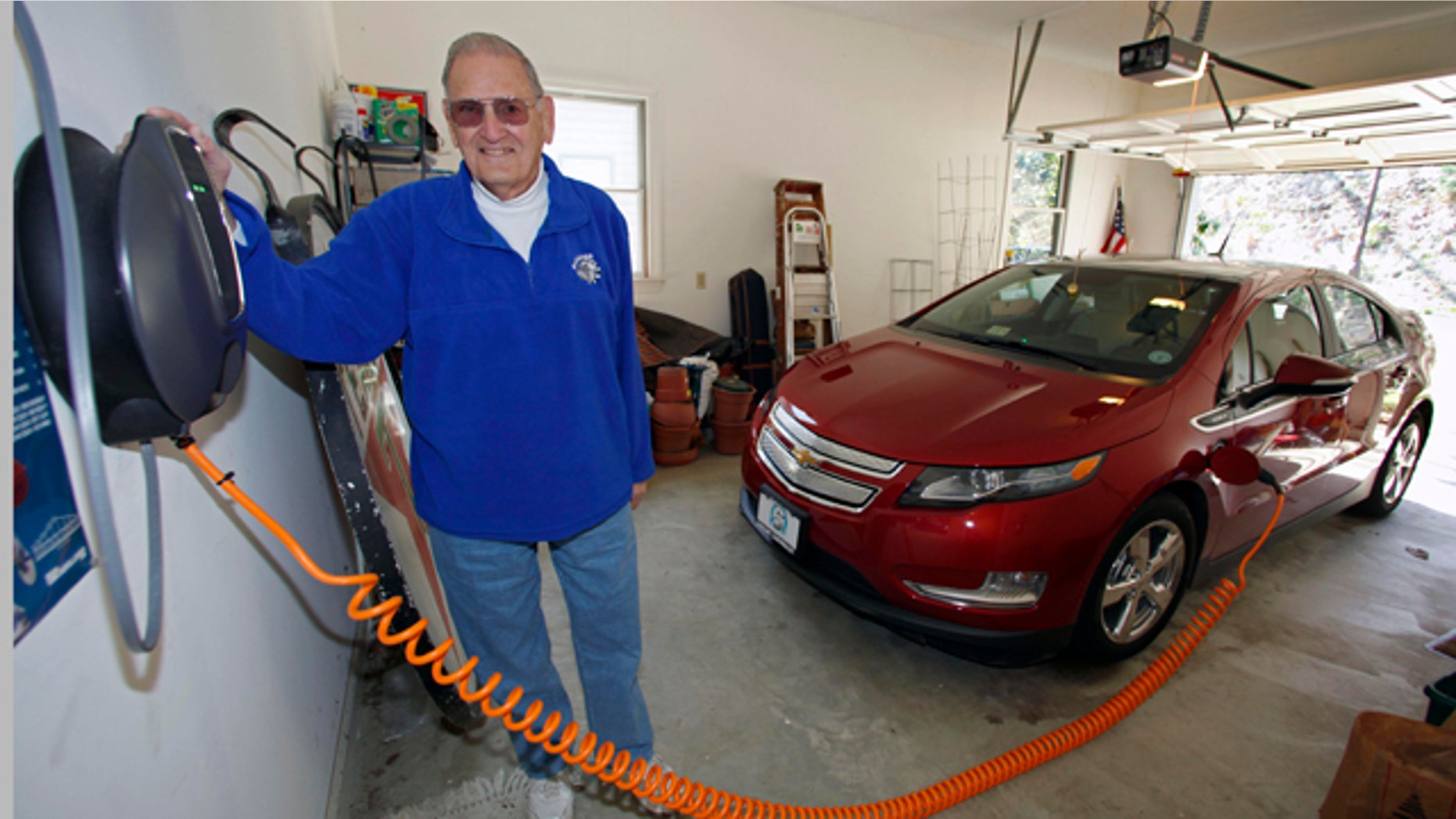 This Friday, March 25, 2011 photo shows James Brazell as he poses with a charging unit for his Chevy Volt electric car at his home in Asheville, N.C. Brazell plugs the car in after short trips. "Pretty much I top it up every time I bring it into the garage," he said. (AP Photo/Chuck Burton)