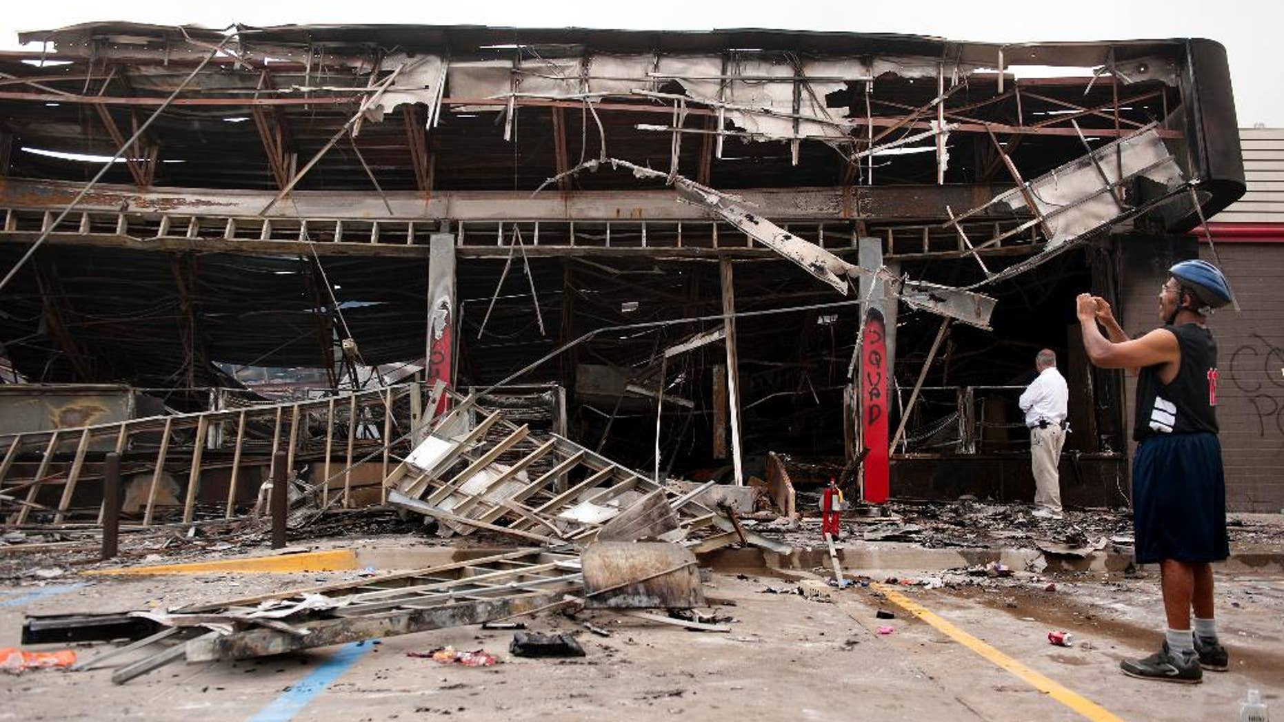 Aug. 11, 2014: Passers-by and media take a closer look at the burned-out shell of the QuikTrip gas station torched during the violence that erupted in Ferguson, Mo. overnight following a candle-light memorial for 18-year-old shooting victim Michael Brown.