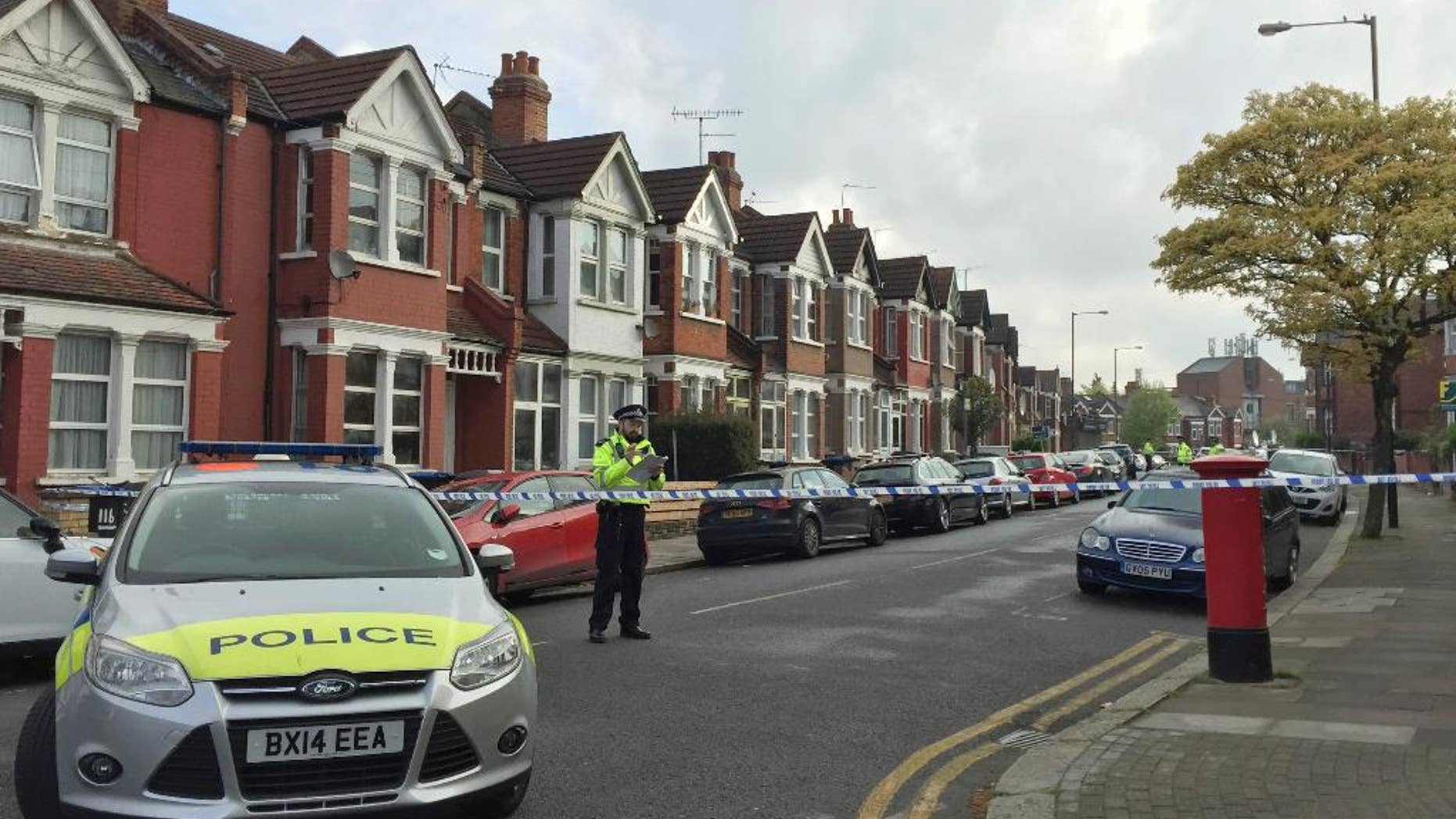 Police officers man the cordoned off area in London's Harlesden Road Friday, April 28, 2017, after British counter-terror police have shot a woman and arrested several people in raids in London and southeastern England. The injured suspect has been hospitalized in serious condition after the raid in northwest London. (Harriet Line/PA via AP)