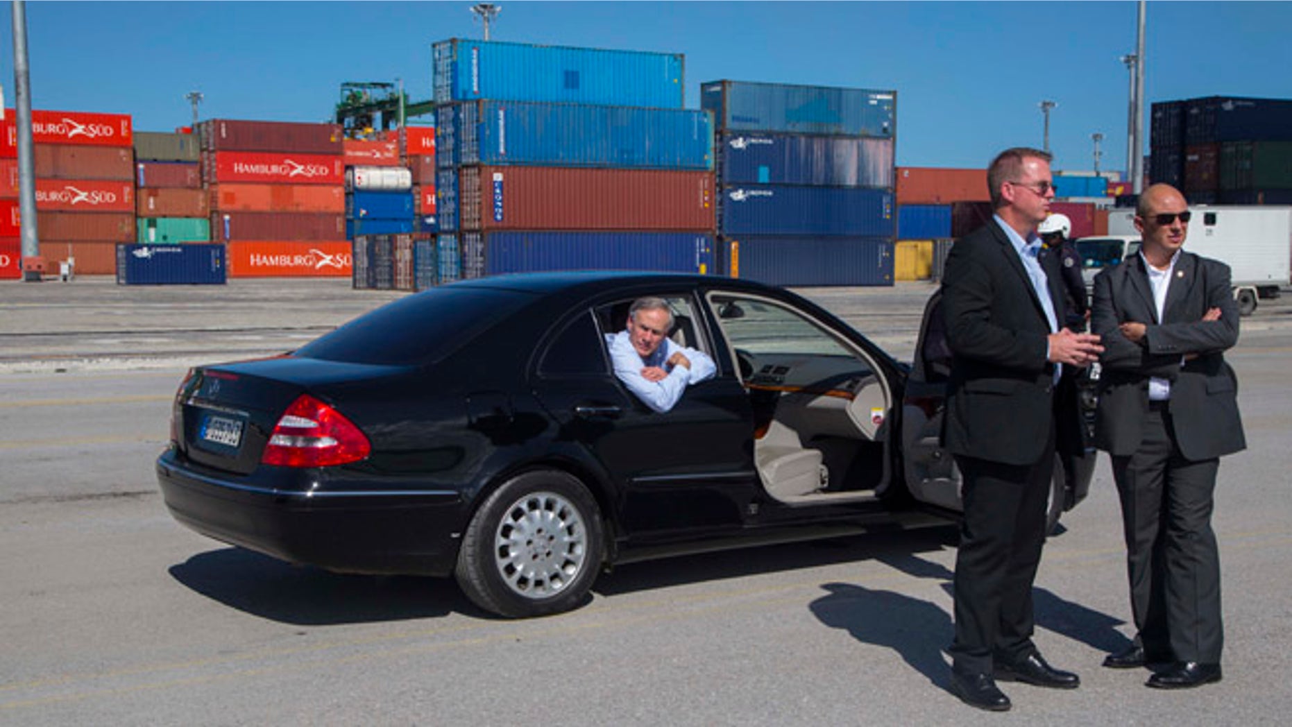 Texas Gov. Greg Abbott looks out from a car with his security detail nearby, during his visit to the Special Development Zone of Mariel, within the Mariel free trade zone in the Bay of Mariel, Cuba, Tuesday, Dec. 1, 2015. Abbott is on a two-day visit to Cuba with a business delegation looking to reintroduce Texas agricultural products to a growing Cuban market. (AP Photo/Desmond Boylan)