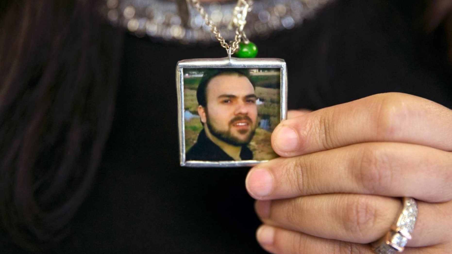 Naghmeh Abedini holds a necklace with a photograph of her husband, Saeed.