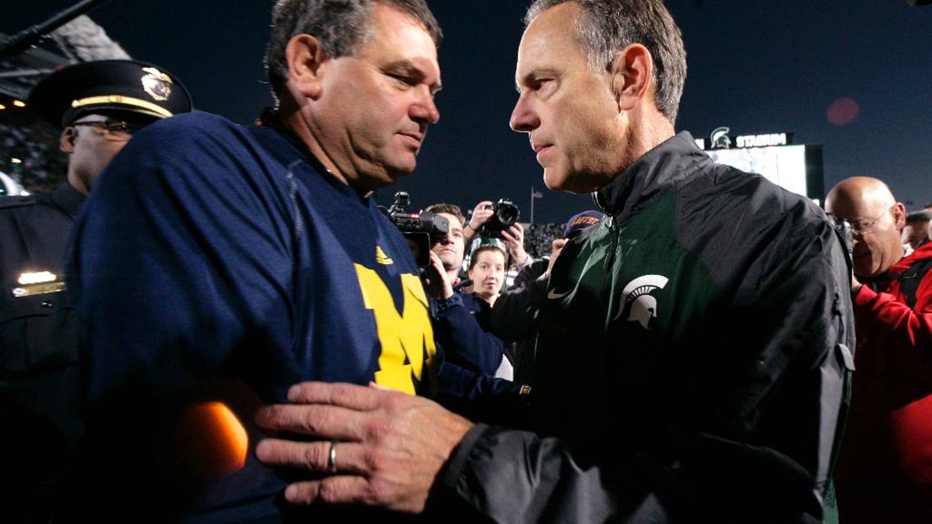 Michigan State coach Mark Dantonio, left, and Michigan coach Brady Hoke talk at midfield before an NCAA college football game, Saturday, Oct. 25, 2014, in East Lansing, Mich. (AP Photo/Al Goldis)
