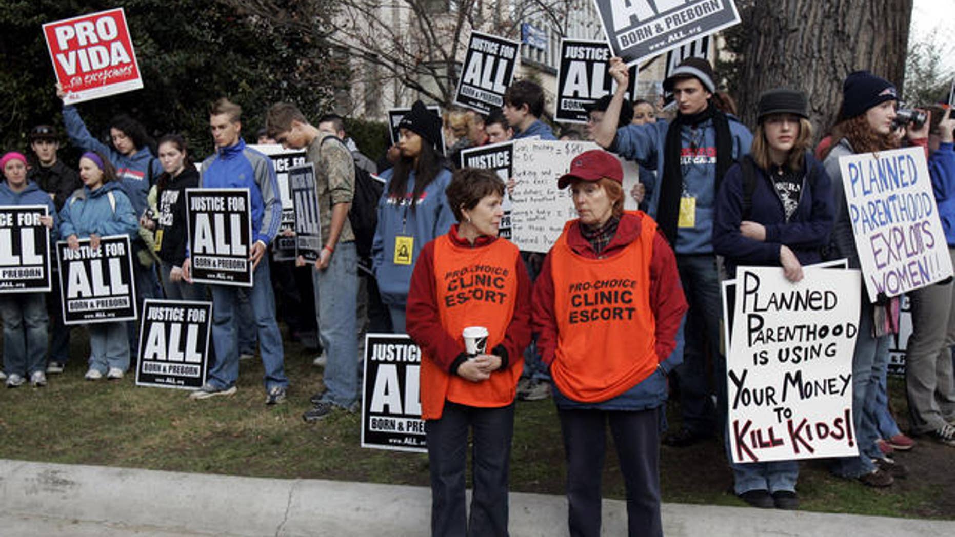 FILE: Planned Parenthood clinic escorts, in orange, stand in front of a group of anti-abortion protestors outside the Planned Parenthood clinic in Washington.
