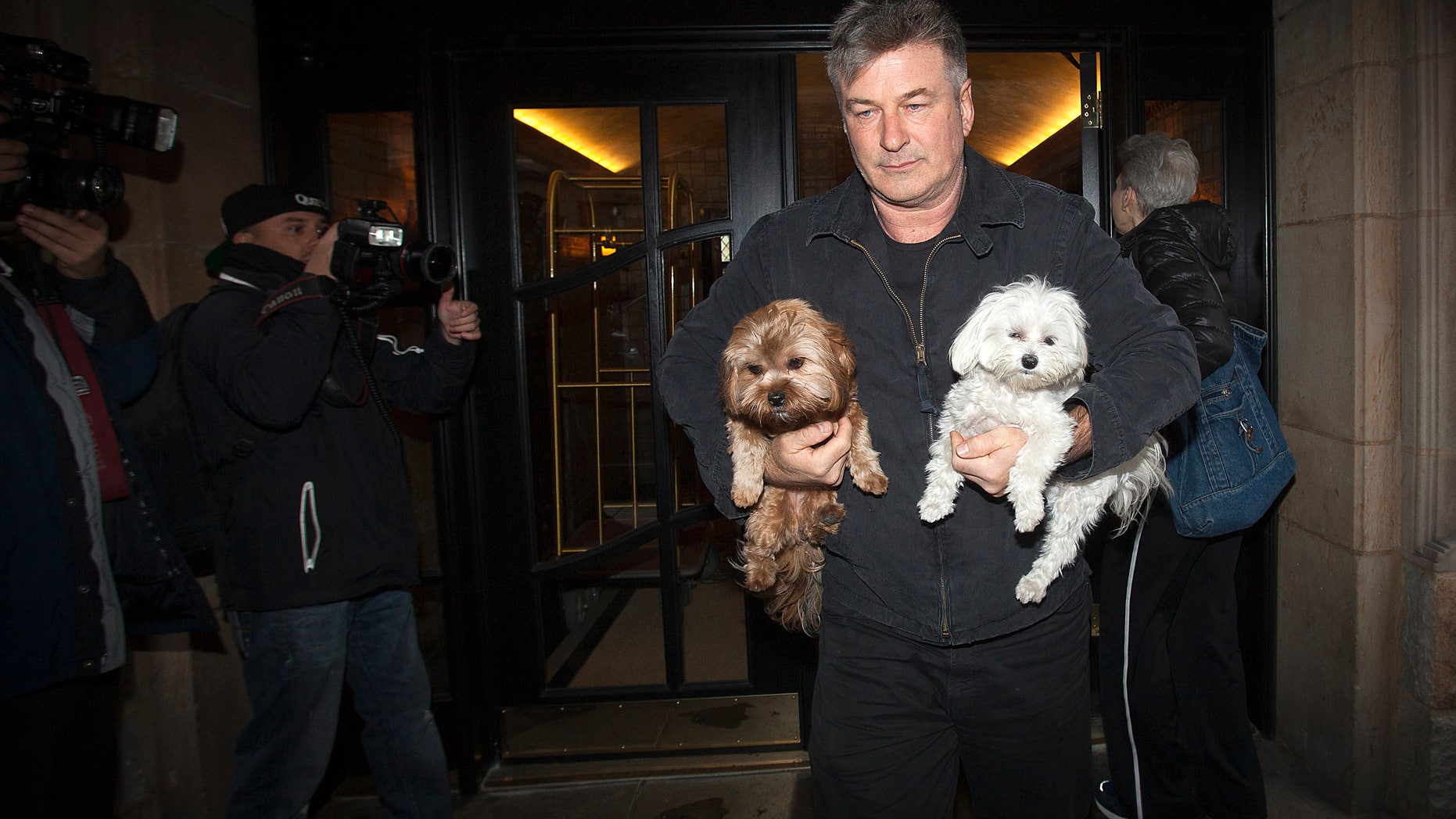 November 15, 2013.Actor Alec Baldwin walks out of his apartment building carrying two dogs in New York. Baldwin assaulted a reporter earlier in the day, according to local media. In the earlier incident, he smacked a mobile phone from the reporter's hands and shoved him against a car.
