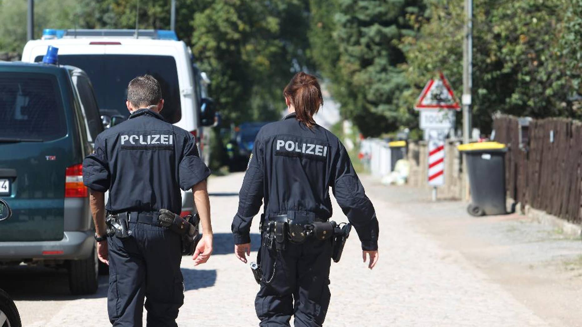 Police officers walk along a road in Reuden, Germany,Thursday Aug. 25, 2016. Three people have been wounded in an armed standoff between police and members of a group that denies the legitimacy of the modern German state in Reuden, eastern Germany. A spokeswoman for police in the eastern state of Saxony-Anhalt says the shootout happened while about 100 police, including a tactical response team, were trying to enforce an eviction order against a 41-year-old “Reich citizen” early Thursday. (Sebastian Willnow/dpa via AP)