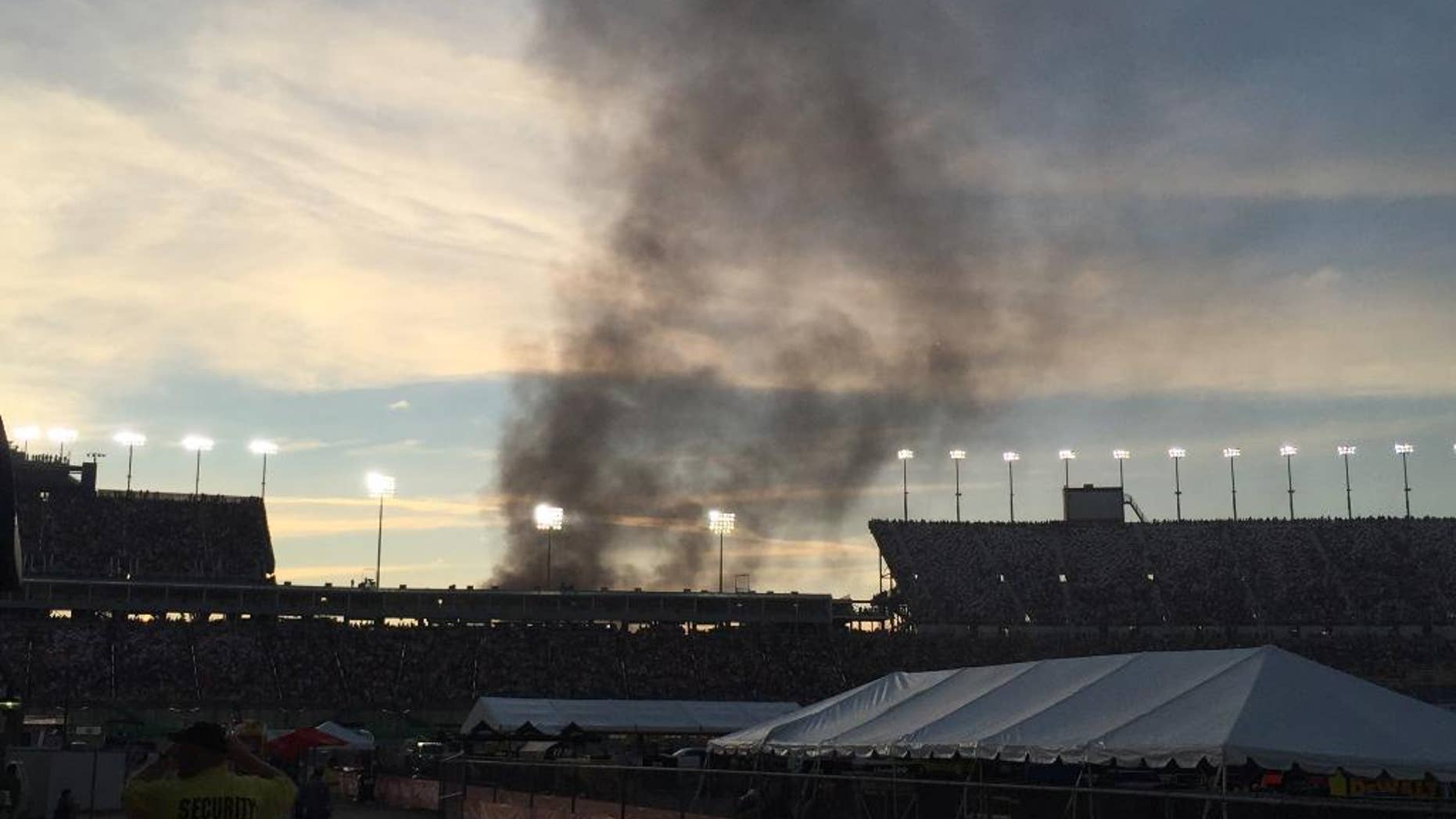 Smoke rises over the main grandstand from a vehicle fire in the platinum parking lot at the NASCAR Sprint Cup Series auto race at Kentucky Speedway, Saturday, July 9, 2016 in Sparta, Ky. (AP Photo/Gary Graves)