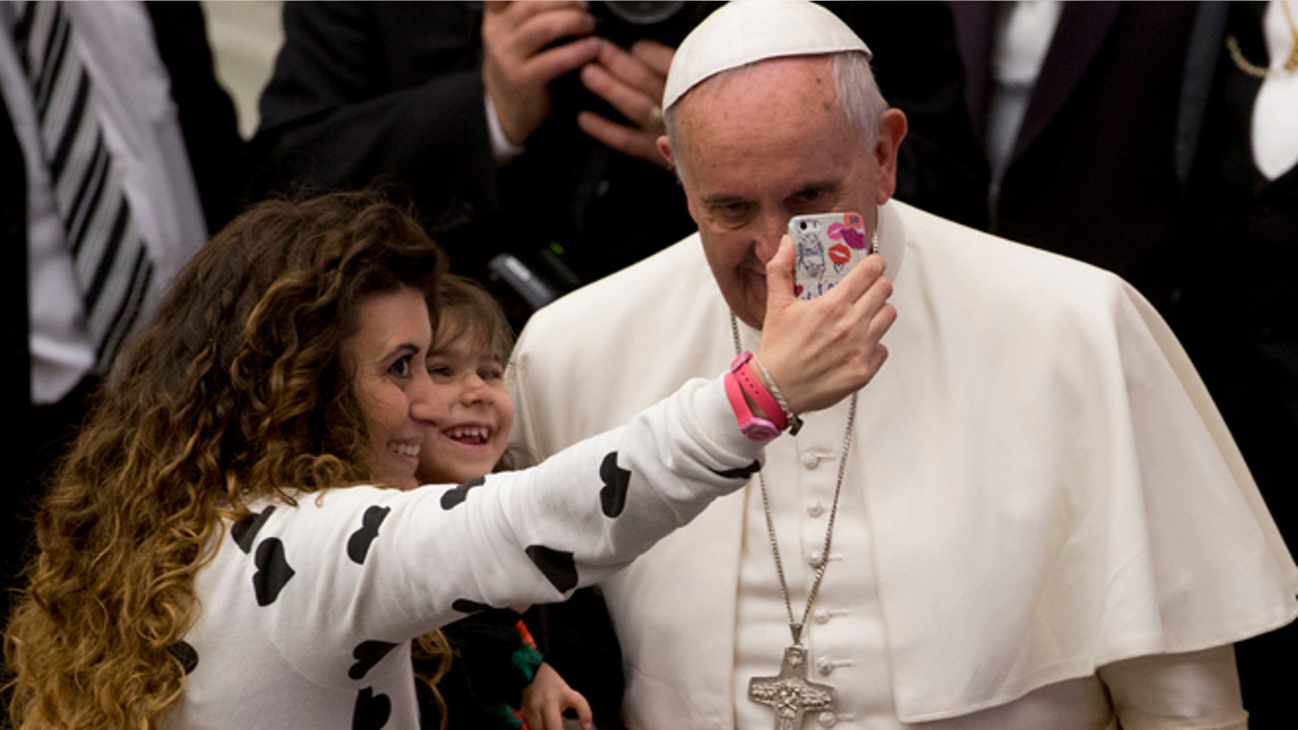 A woman and a child take a selfie photo with Pope Francis, right, during his weekly general audience in the Paul VI hall at the Vatican, Wednesday, Jan. 21, 2015. Pope Francis is praising big families after saying Catholics don't have to breed "like rabbits." He says big families are a gift and don't cause poverty in the developing world, and that the real cause of poverty is an unjust economic system that idolizes money over people. (AP Photo/Andrew Medichini)