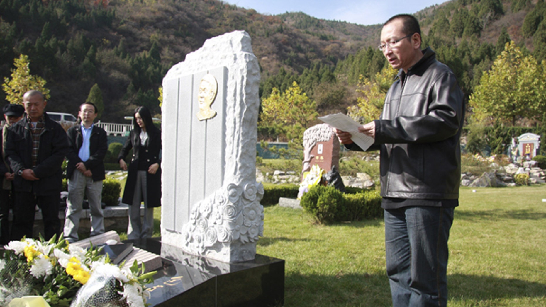 This Oct. 28, 2008 photo shows Liu Xiaobo, right, reading a letter beside the grave of Bao Zunxin, a Chinese historian and political dissident who was arrested and jailed for his role in the 1989 Tiananmen Square democracy protests in Beijing, China.