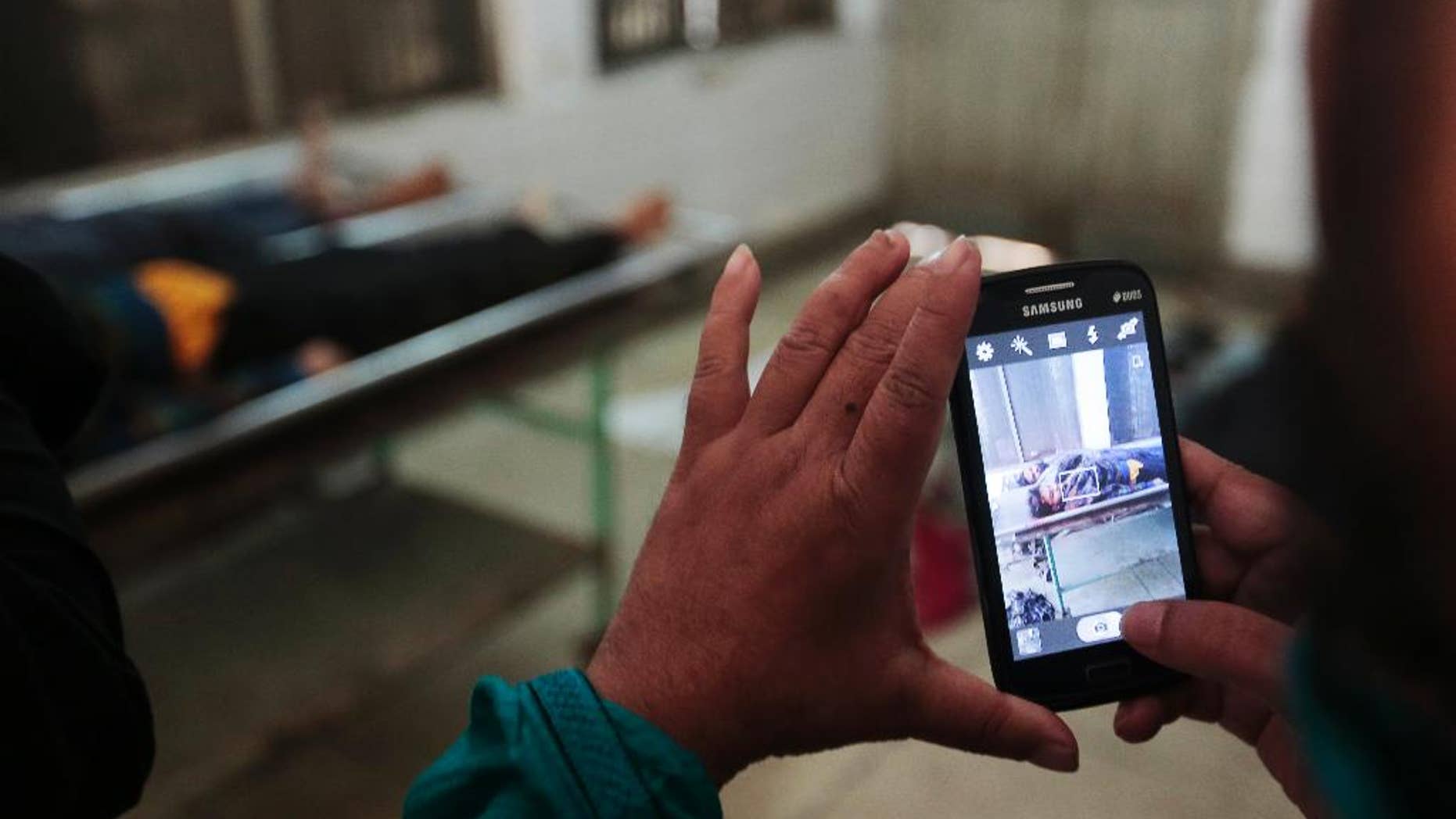 A Bangladeshi security officer takes photographs of bodies of suspected militants at a morgue in Dhaka, Bangladesh, Friday, Jan. 6, 2017. Bangladesh police say a militant suspected of being one of the leaders of an attack on a popular cafe in Bangladesh's capital last summer that left 20 people dead has been killed in a shootout with security officials. (AP Photo)