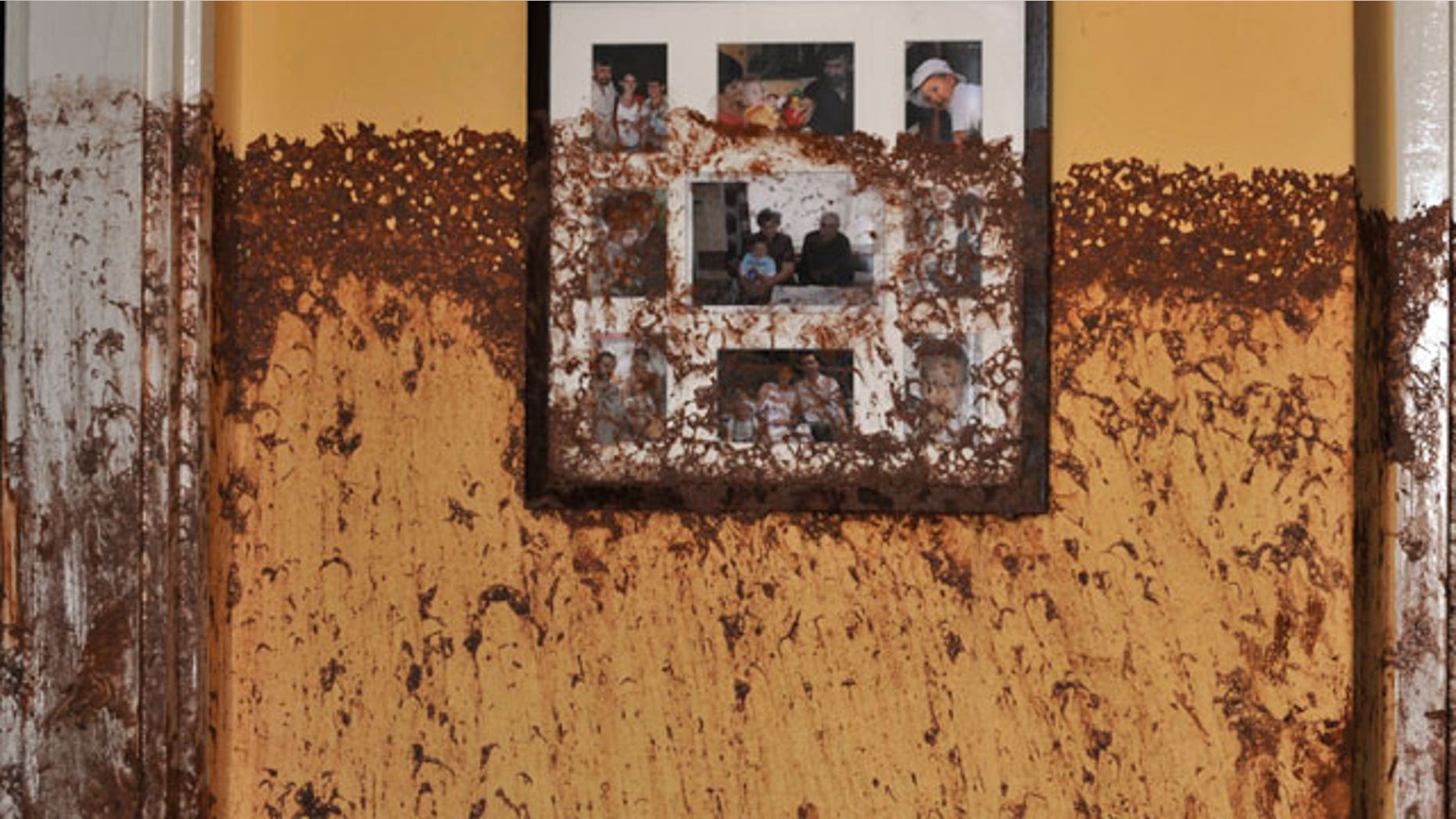 Family photos on a wall show the height of the sludge after a flood of toxic mud broke into a home in the village of Kolontar, Hungary, Thursday, Oct. 7, 2010. Monday's flooding was caused by the rupture of a red sludge reservoir at a metals works in western Hungary and has affected seven towns near the Ajkai, 100 miles (160 kilometers) southwest of Budapest. The flood of toxic mud killed a yet unknown number of people, injured more than one hundred, with some people still missing.