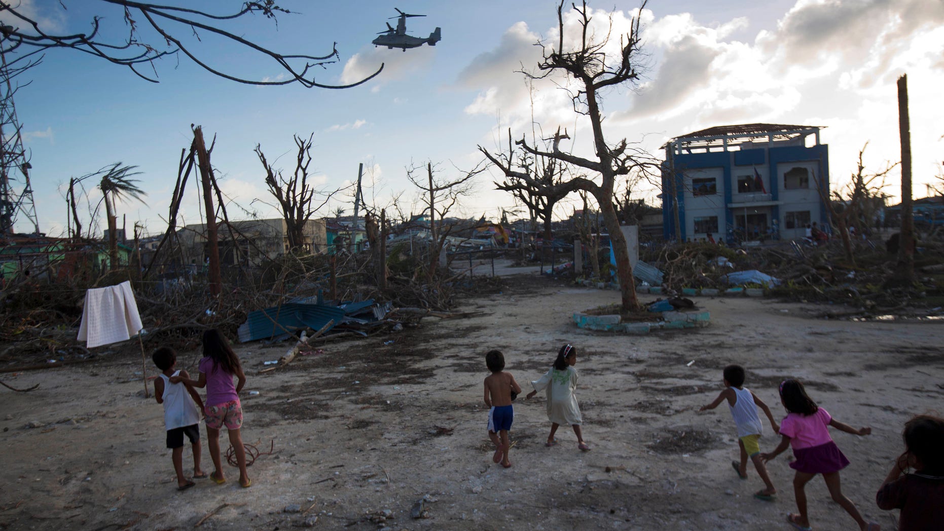FILE--In this Thursday, Nov. 14, 2013 file photo, children run towards a U.S. military aircraft as it arrives to distribute aid to Typhoon Haiyan survivors in the destroyed town of Guiuan, Philippines on Thursday, Nov. 14, 2013. Though aid has started to arrive in Guiuan, in the nearby town of Marabut residents complained that aid has been far too slow to come (AP Photo/David Guttenfelder, File)