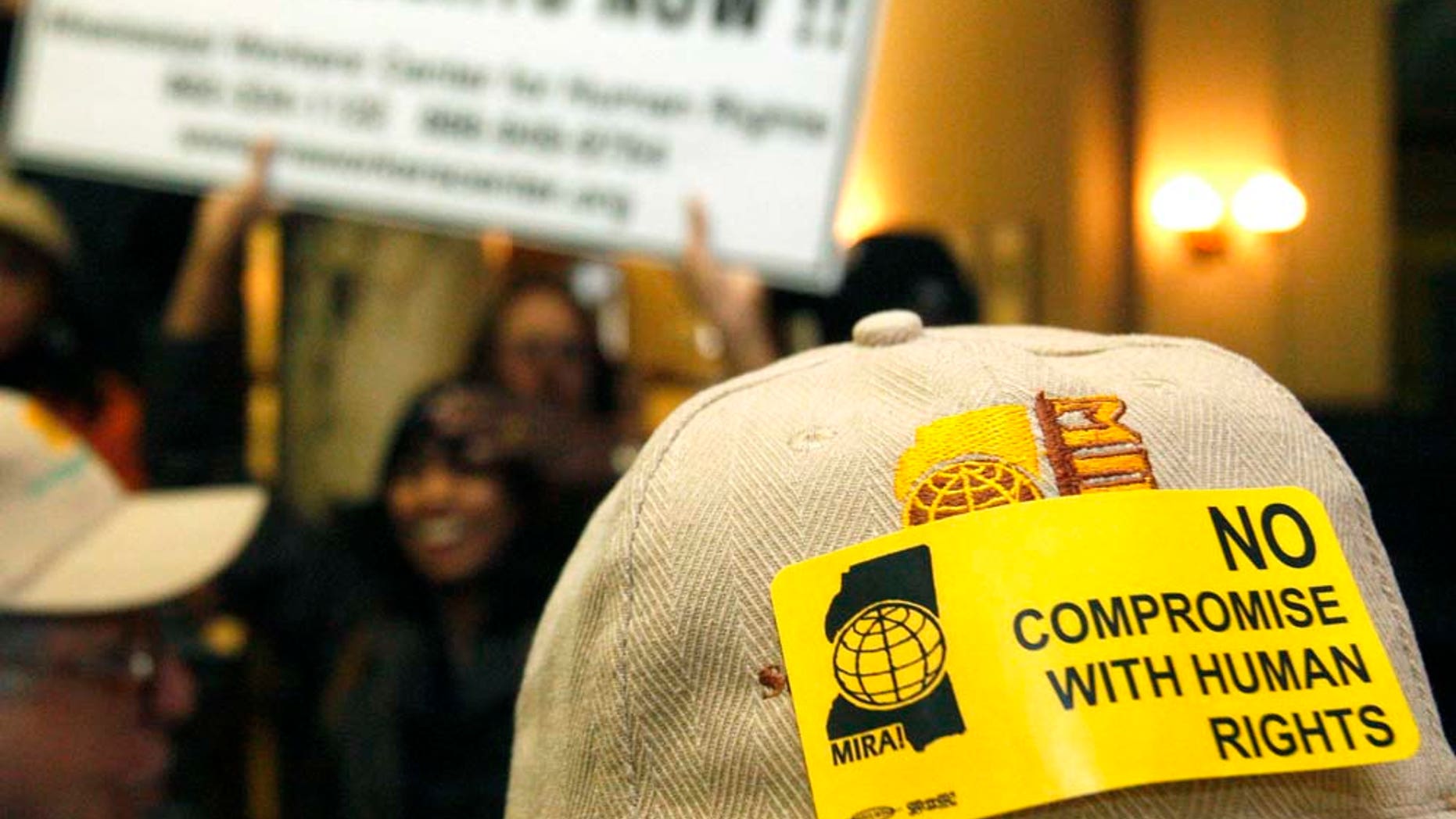 A hat sticker and sign carried by members of the Mississippi Immigrants Rights Alliance at a news conference and rally at the Capitol in Jackson, Miss., Wednesday, Jan. 12, 2011 tells of their opposition to a bill that would allow law officers to check for immigration status if they stop people for traffic offenses or other reasons. (AP Photo/Rogelio V. Solis)