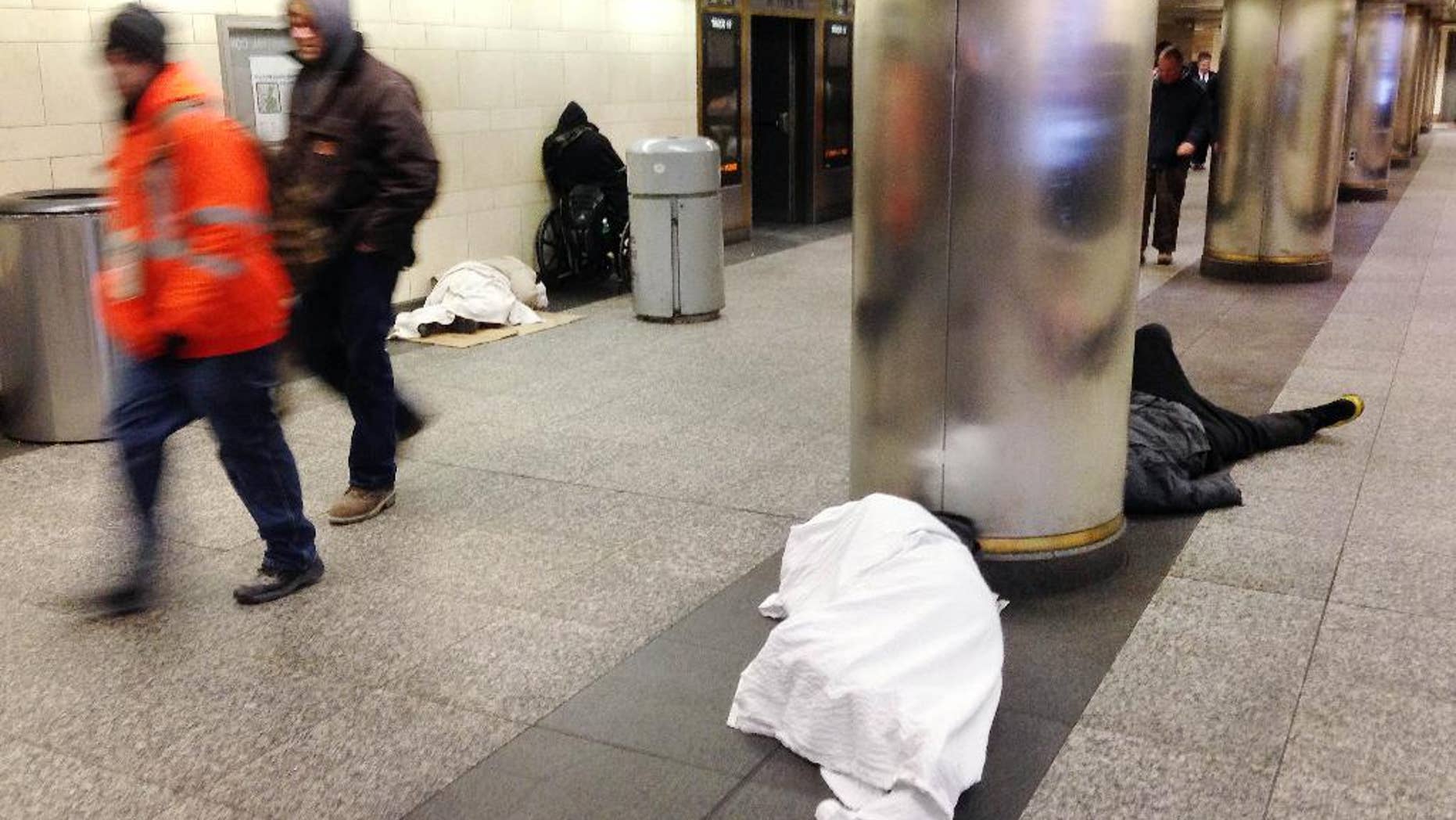 Jan. 8, 2015: Homeless people, seeking shelter from the cold, sleep on the floor of New York's Penn Station as commuters walk past. (AP)