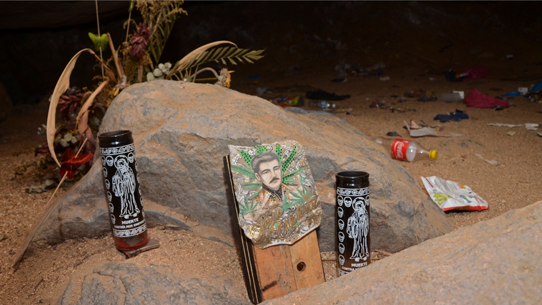 June 8: Candles depicting the "Santa Muerte" and an image of Jesus Malverde, center, stand at the entrance of a cave near the site where mass graves were found in the Pacific resort city of Acapulco, Mexico. (AP Photo/Bernandino Hernandez)