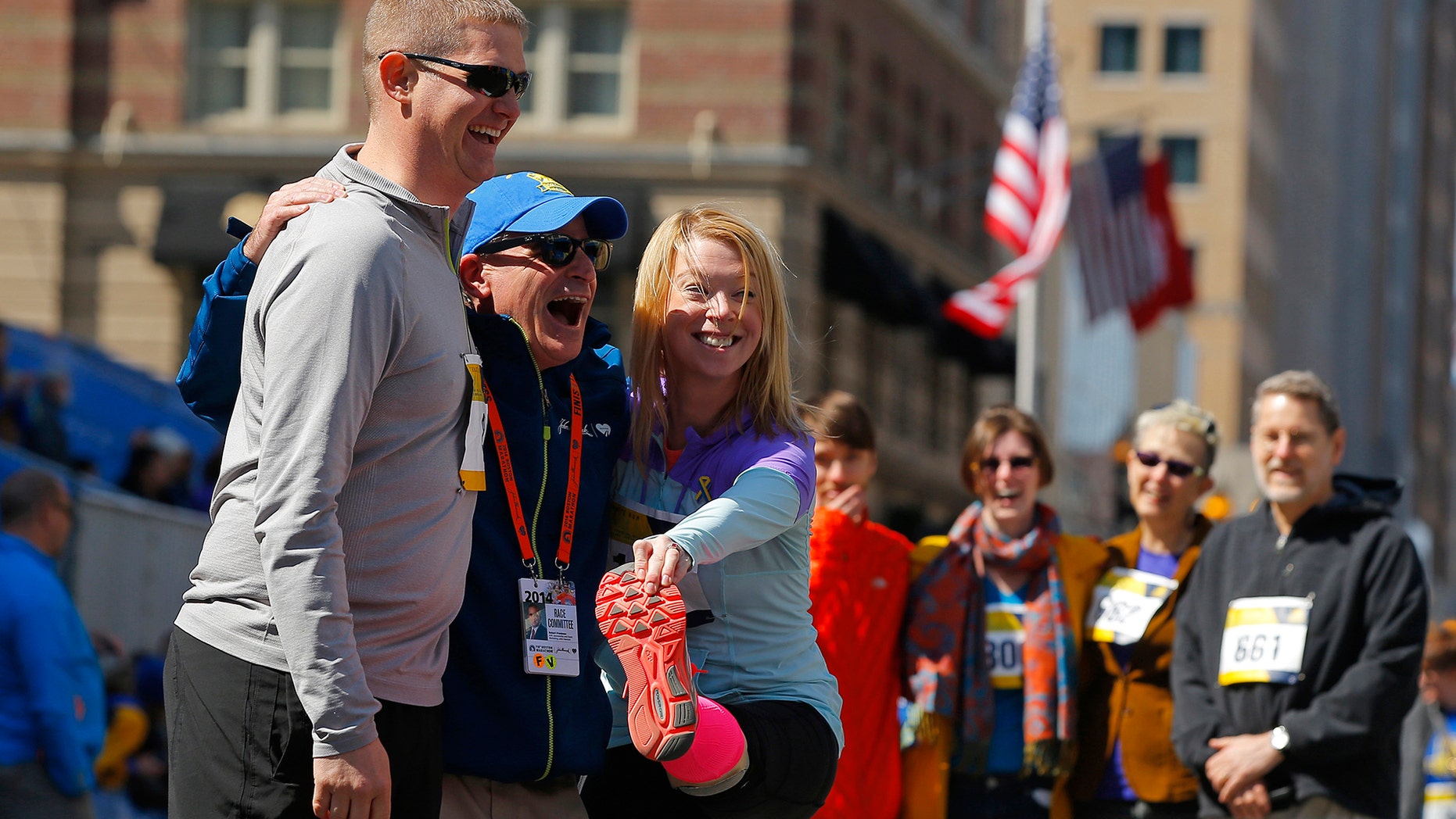 2013 Boston Marathon bombing survivor Adrianne Haslet-Davis (3rd L) and her husband Adam Davis (L) pose for a photograph after crossing the marathon finish line during a Tribute Run for survivors and first responders in Boston, Massachusetts April 19, 2014.