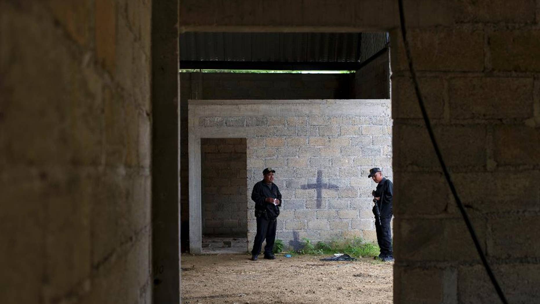 FILE - In this July 3, 2014, file photo, state police stand inside a warehouse where a black cross covers a wall near blood stains on the ground, after a shootout between Mexican soldiers and alleged criminals on the outskirts of the village of San Pedro Limon, in Mexico state, Mexico. Leading Mexican human rights groups announced Wednesday, March 30, 2016, that a military court acquitted six of seven soldiers charged with breach of discipline in the 2014 killings. (AP Photo/Rebecca Blackwell, File)
