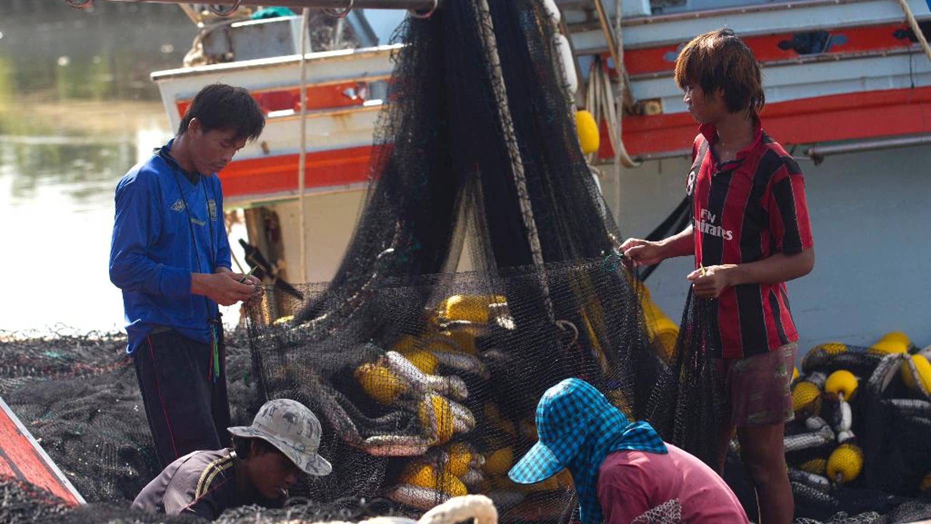 FILE - In this Sept. 3, 2013 file photo, migrant workers from Myanmar clean fishing nets aboard a trawler after a fishing trip in the Gulf of Thailand in Samut Sakhon Province, west of Bangkok, Thailand. The European Union says Thailand must take “swift and determined action” by next month to improve its fisheries and labor practices or the threat of a seafood ban will come closer.(AP Photo/Sakchai Lalit, File)