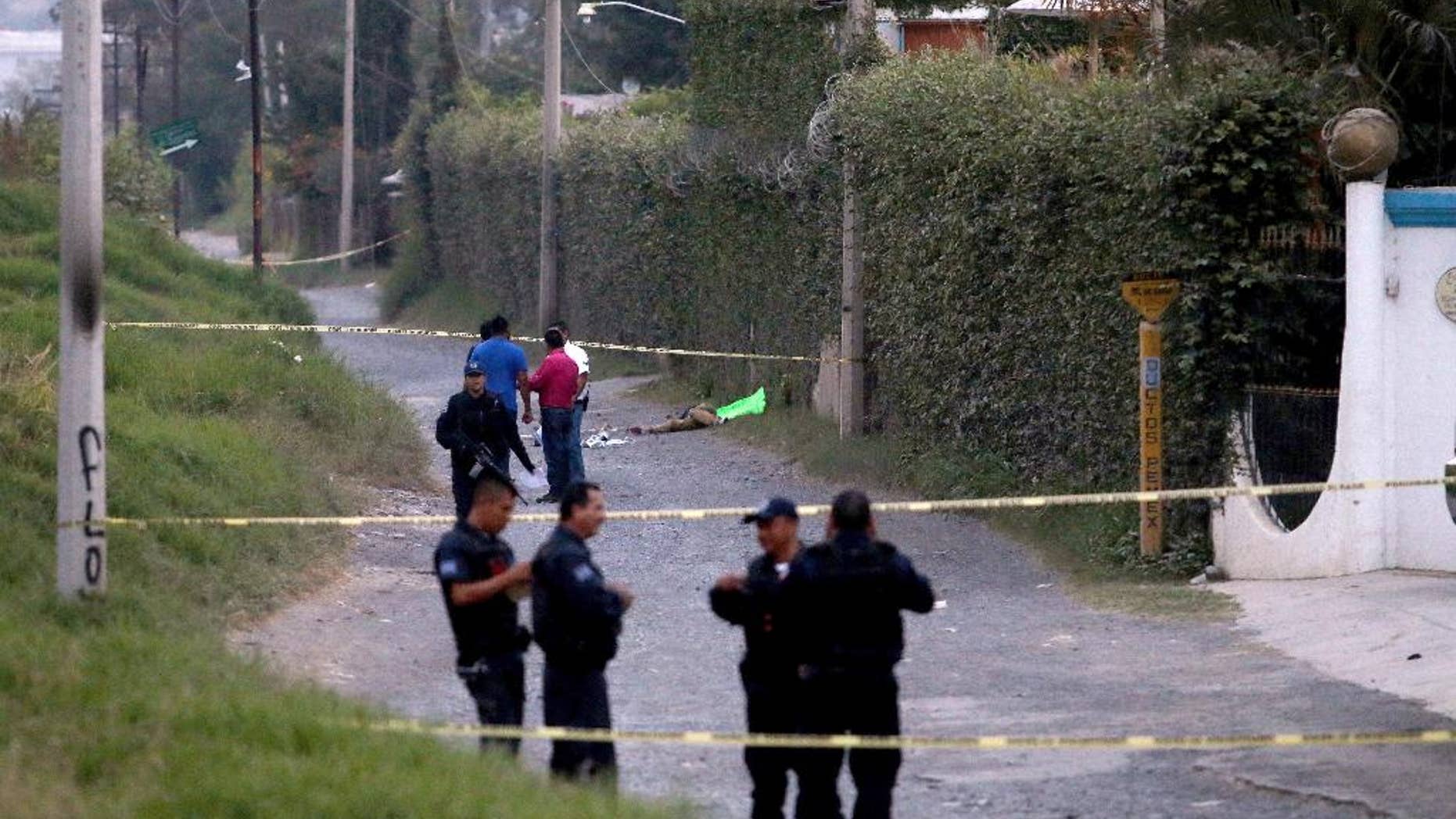 Police secure the area where six people were found alive with their hands cut off, along with another person who was killed, in the background, in Tlaquepaque on the outskirts of Guadalajara, Mexico, Tuesday, Oct. 18, 2016. Investigators believe the mutilations and the killing were revenge for an unpaid drug payment involving members of the same cell of a criminal group. (AP Photo/Fernando Carranza)
