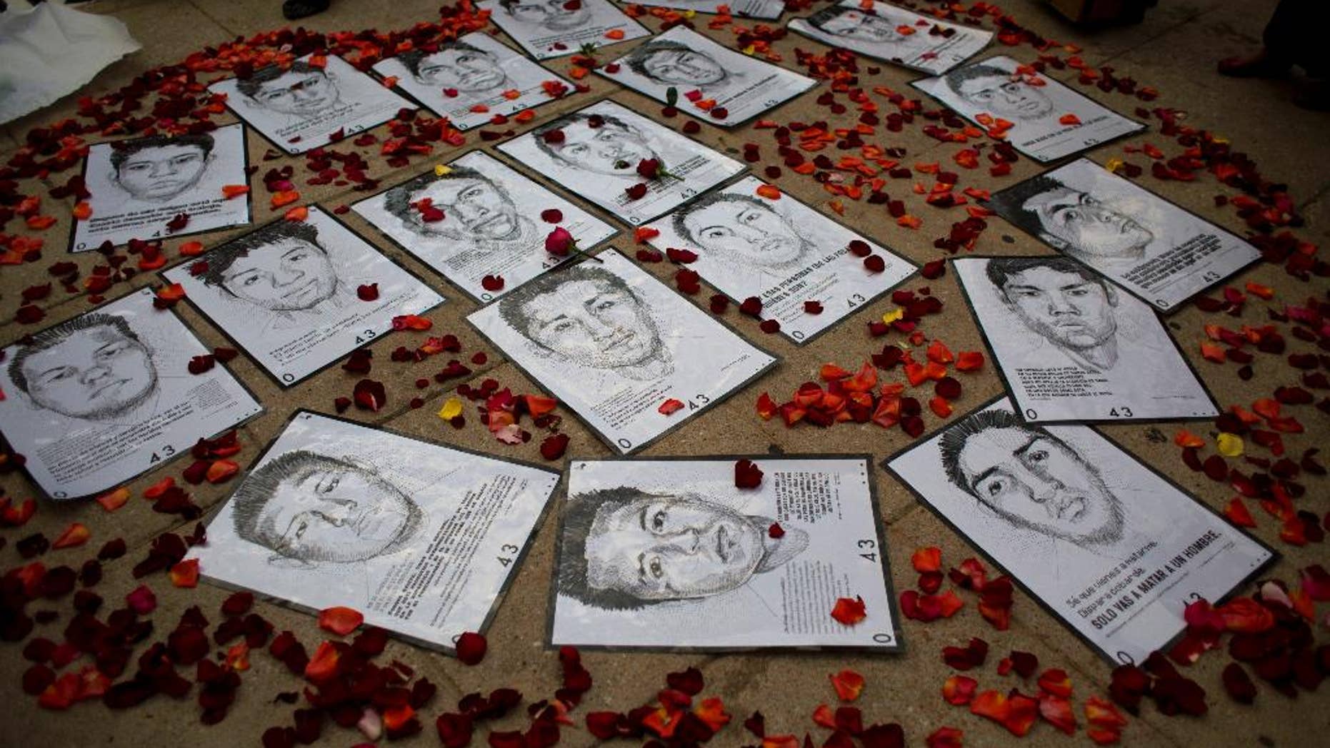 FILE - This Thursday, March 26, 2015 file photo shows drawings of some of 43 missing rural college students are surrounded by flower petals, forming the shape of a heart, during a protest marking the six-month anniversary of their disappearance, in Mexico City. Angry citizens and parents of the 43 missing students urged the country not to abandon them. (AP Photo/Rebecca Blackwell, File)