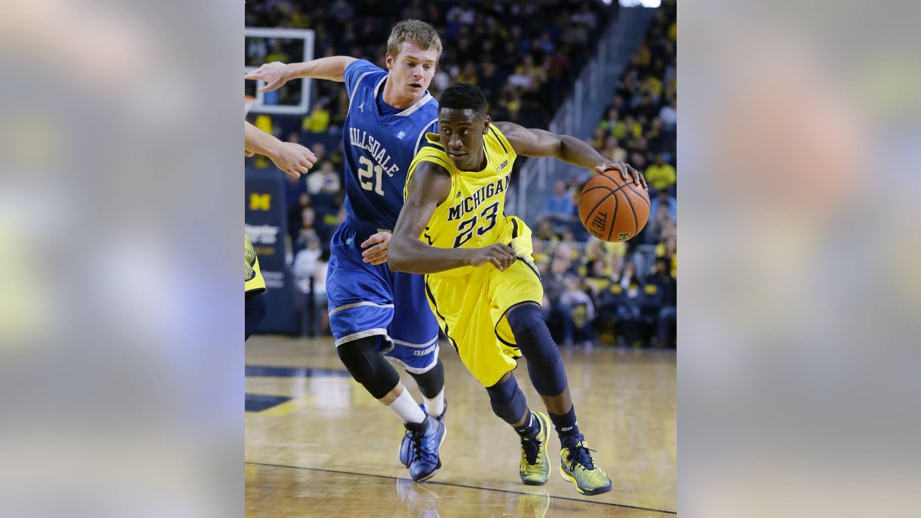 Michigan guard Caris LeVert (23) drives on Hillsdale forward Lucas Grose (21) during the first half of an NCAA college basketball game in Ann Arbor, Mich., Saturday, Nov. 15, 2014. (AP Photo/Carlos Osorio)