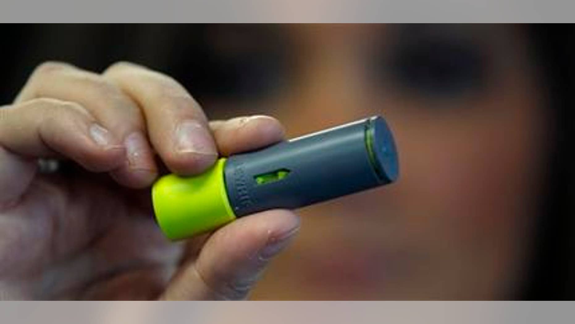 A woman holds up a "Aero Shot" caffeine device in Boston, Tuesday Feb. 7, 2012. The lipstick-sized product went on the market late last month in Massachusetts and New York, and is also available in France. A single unit costs $2.99 at convenience, mom-and-pop, liquor and online stores. (AP Photo/Charles Krupa)