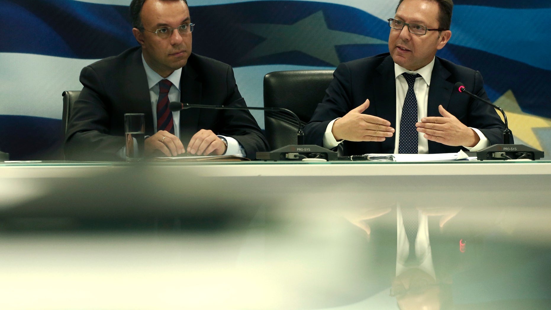 Greek Finance Minister Yiannis Stournaras, right, speaks next to Deputy Finance Minister Christos Staikouras during a press conference about Greece's EU presidency in Athens, on Tuesday, Jan. 7, 2014. Greek authorities have imposed an 18-hour ban on protests across the center of Athens during events planned Wednesday to mark the inauguration of the nation's six-month presidency of the European Union.(AP Photo/Petros Giannakouris)