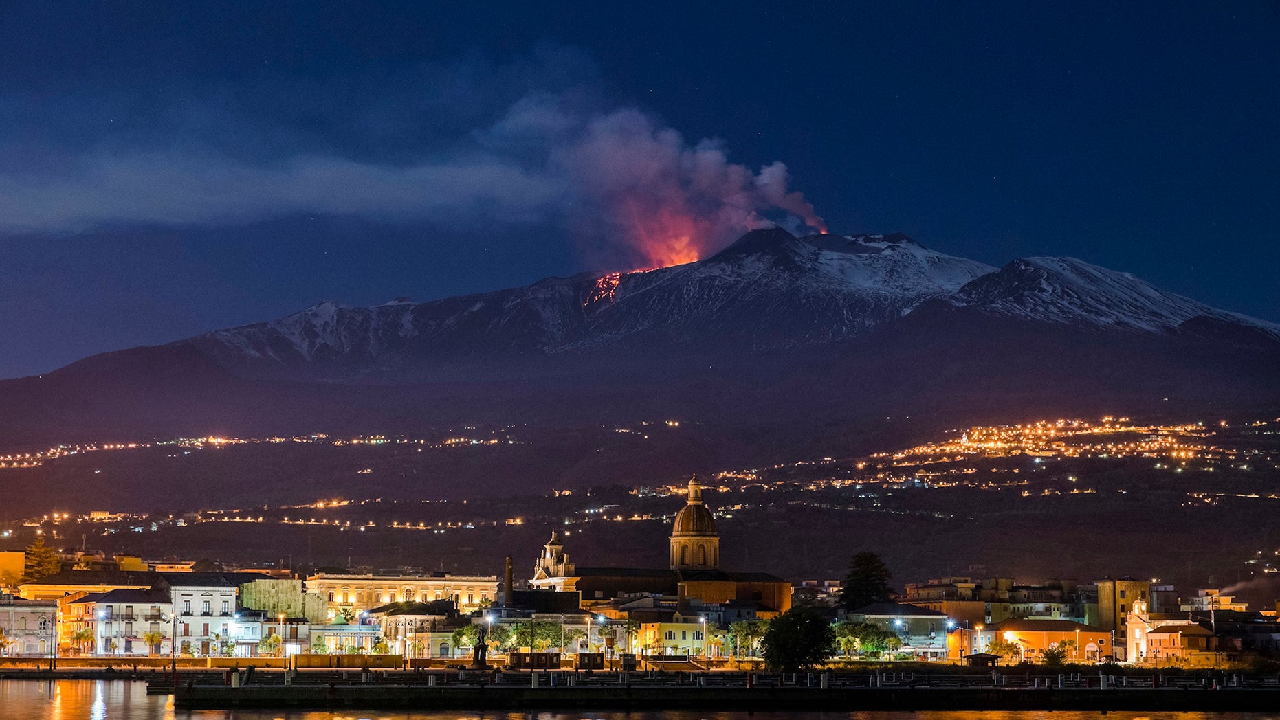 Mount Etna, Europe's most active volcano, spews lava as the Sicilian town of Riposto, Italy, is visible in foreground, during an eruption in the early hours of Tuesday, April 11, 2017