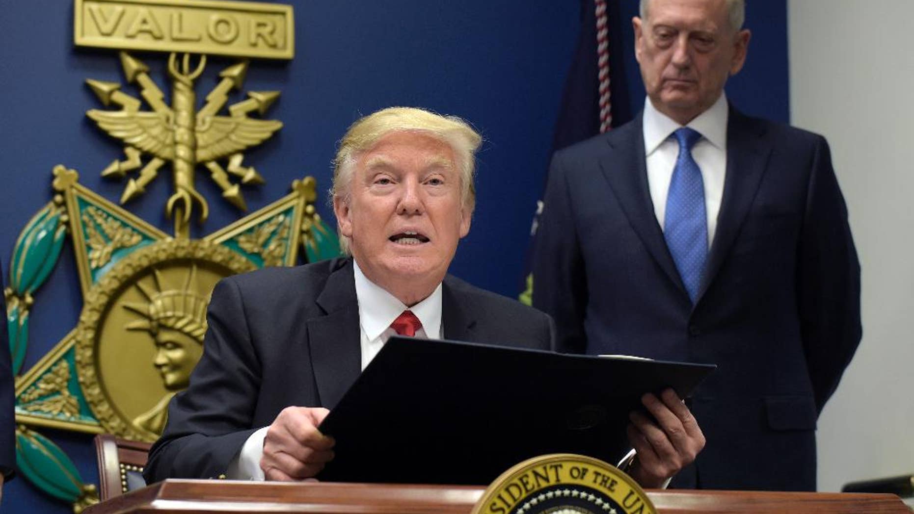 FILE - In this Jan. 27, 2017 file photo, President Donald Trump, left, with Defense Secretary James Mattis, right, watching, explains the executive action on extreme vetting that he is about to sign at the Pentagon in Washington. American forces were perched high on the top of the Bashiq Mountain, calling in airstrikes that pounded Islamic State militants. Down below, Kurdish forces rolled past to recapture in the ancient city of Sinjar. (AP Photo/Susan Walsh)