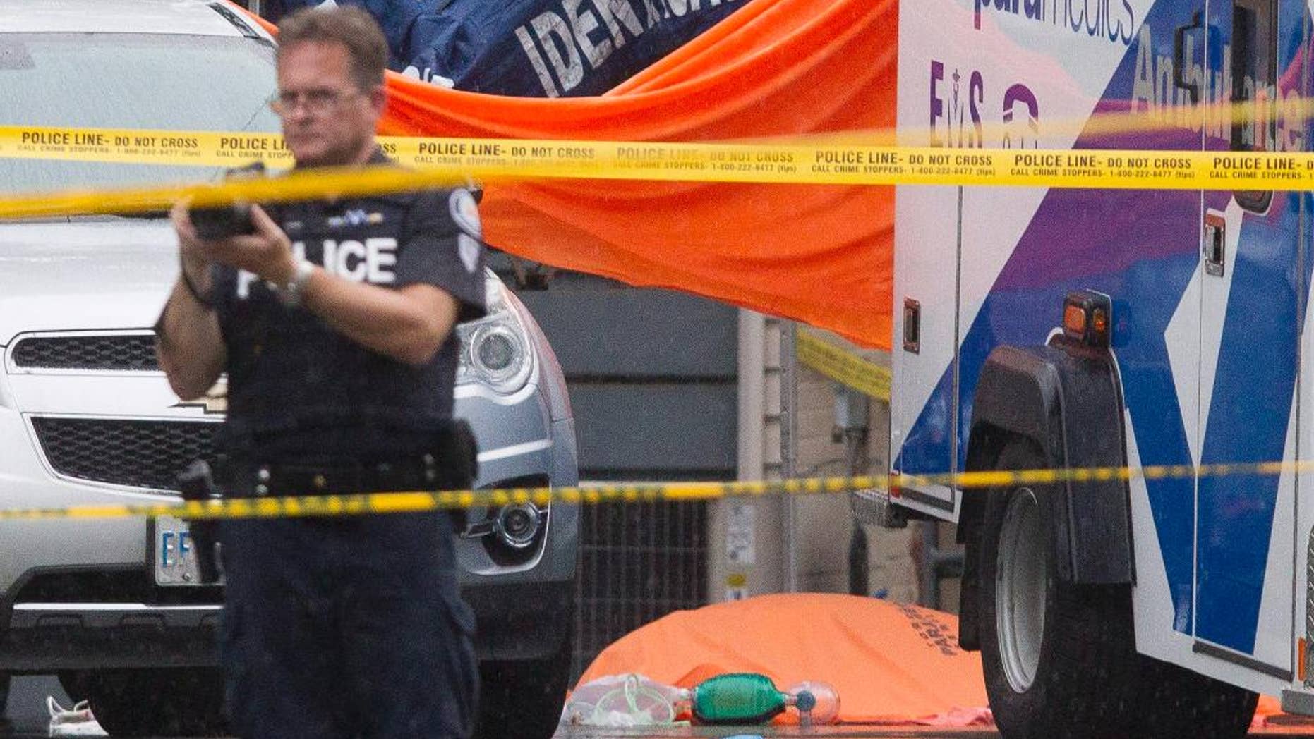 A covered body lies covered in front of a house in Scarborough, Ontario, Thursday, Aug. 25, 2016. Three people were killed in what Canadian police on Thursday called a homicide that may have involved a crossbow. (Chris Young/The Canadian Press via AP)