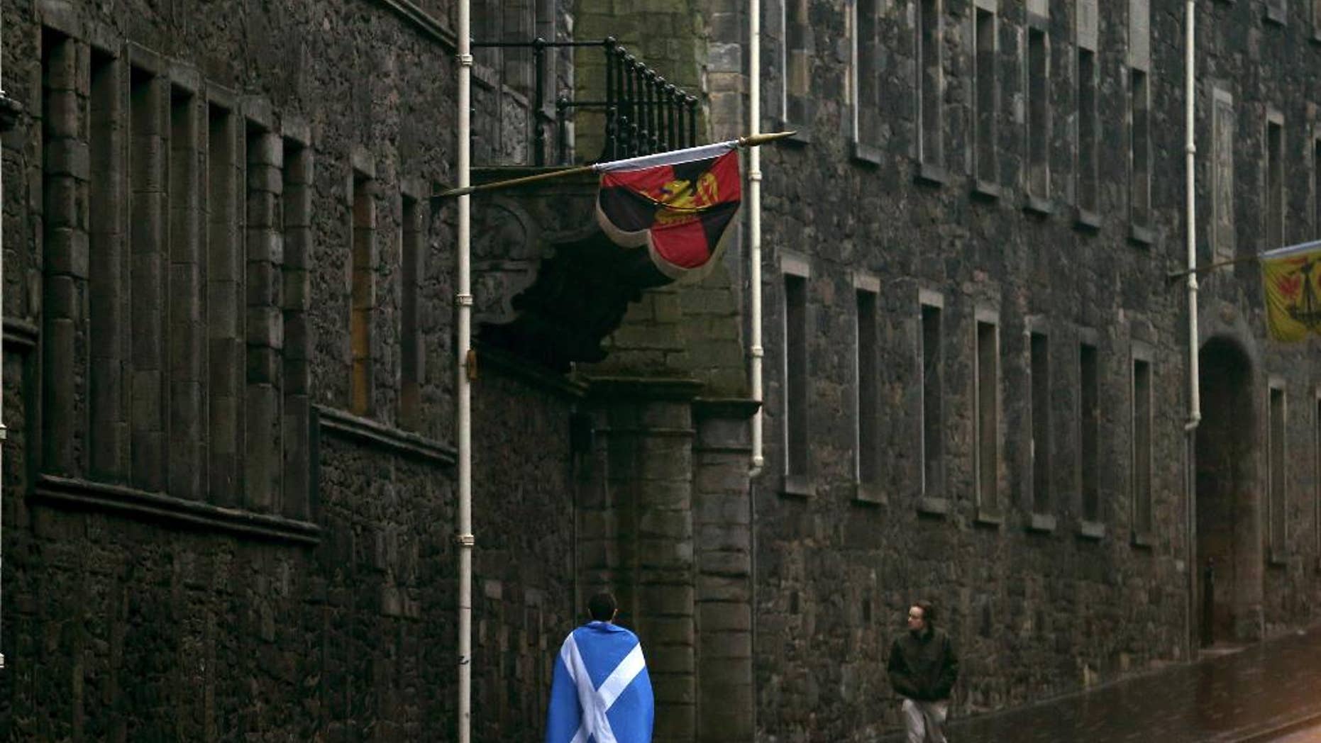 A man draped in a Saltire walks up the Royal Mile in Edinburgh, Scotland, Friday, Sept. 19, 2014. Scottish voters have rejected independence and decided that Scotland will remain part of the United Kingdom. The result announced early Friday was the one favored by Britain's political leaders, who had campaigned hard in recent weeks to convince Scottish voters to stay. It dashed many Scots' hopes of breaking free and building their own nation. (AP Photo/Scott Heppell)