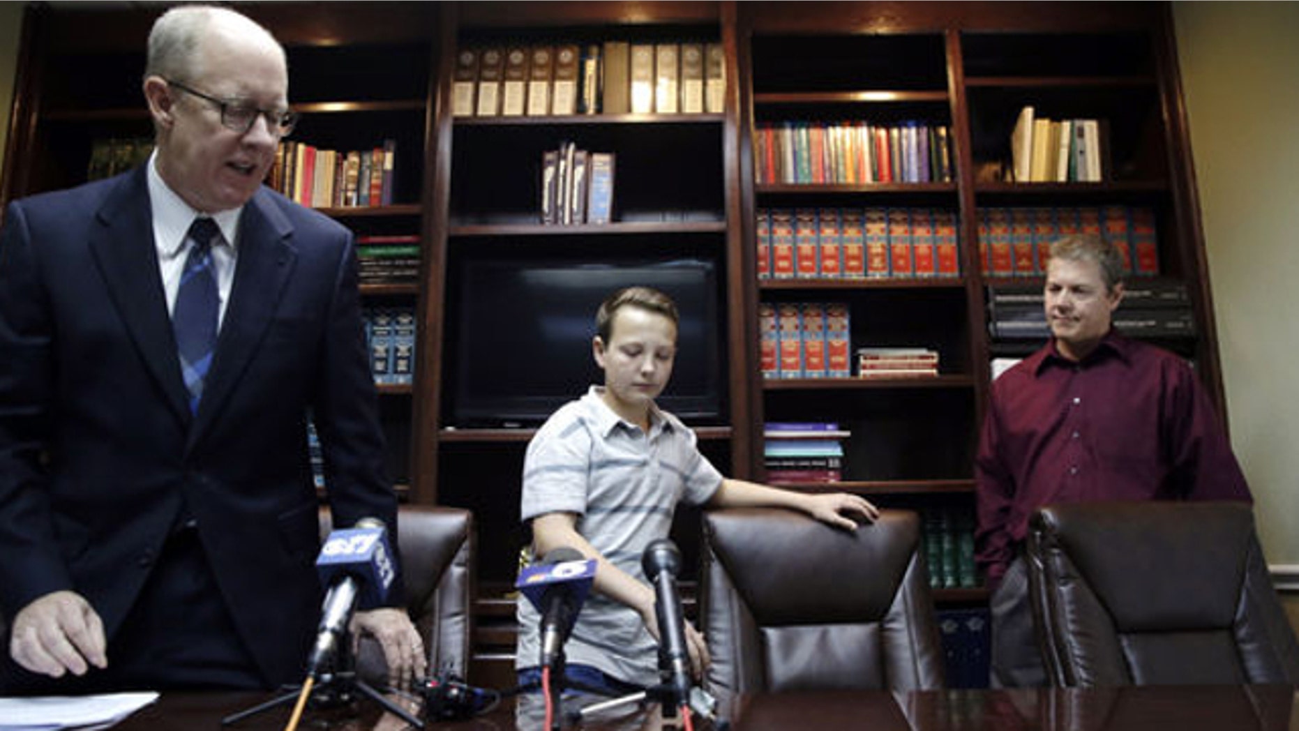 March 26, 2014: Lucas McConnell, 13, center, takes a seat before speaking to reporters with his attorney Todd Clement, left, and his father Kevin McConnell by his side in Burleson, Texas.