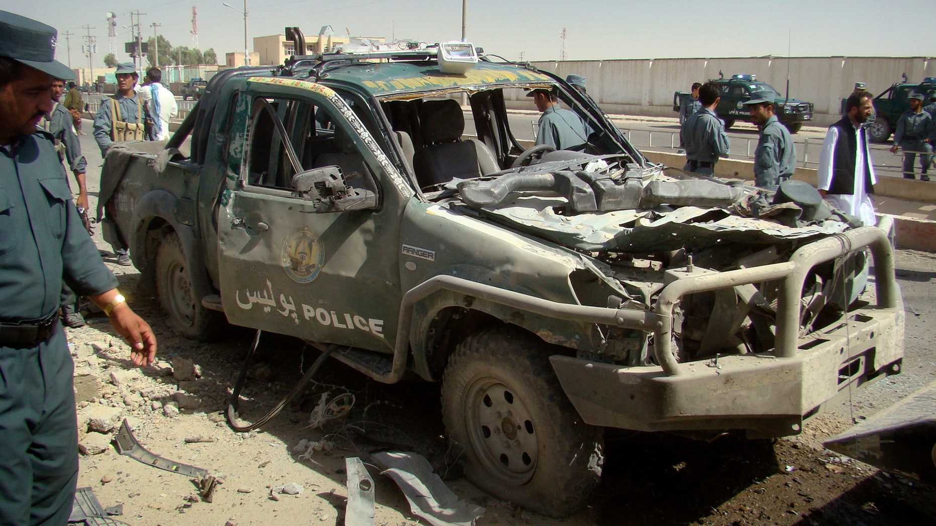 Sept. 27: An Afghan police officer, left, looks at a police vehicle damaged in a suicide attack in Lashkar Gah, Helmand province, Afghanistan. A suicide bomber rammed a car packed with explosives into a police truck outside a bakery in southern Afghanistan on Tuesday, killing a number of civilians, officials said.