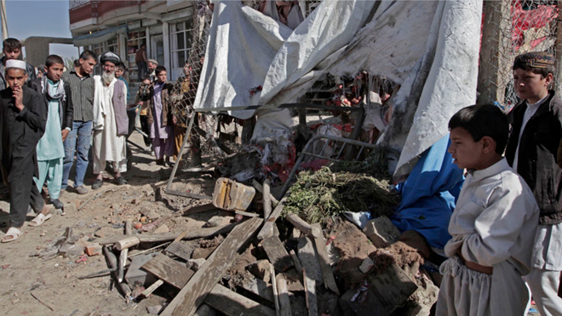 Oct. 27, 2013: Afghans look at wreckage after a roadside bomb explosion went off on the outskirts of Kabul, Afghanistan. An Afghan official and witnesses say a roadside bomb, apparently targeting a group of soldiers, has killed a civilian in a market in the capital Kabul, the bomb went off Sunday as soldiers and officers for their vehicle to take them toward their work place.