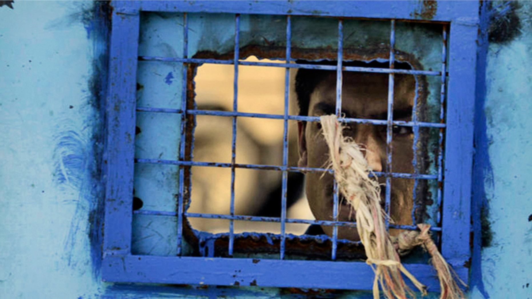 In this Monday, April 25, 2011 file photo, a prisoner looks out of his cell window at the main prison in Kandahar, Afghanistan. The United Nations said Sunday that Afghan authorities were still torturing prisoners, such as hanging them by their wrists and beating them with cables.
