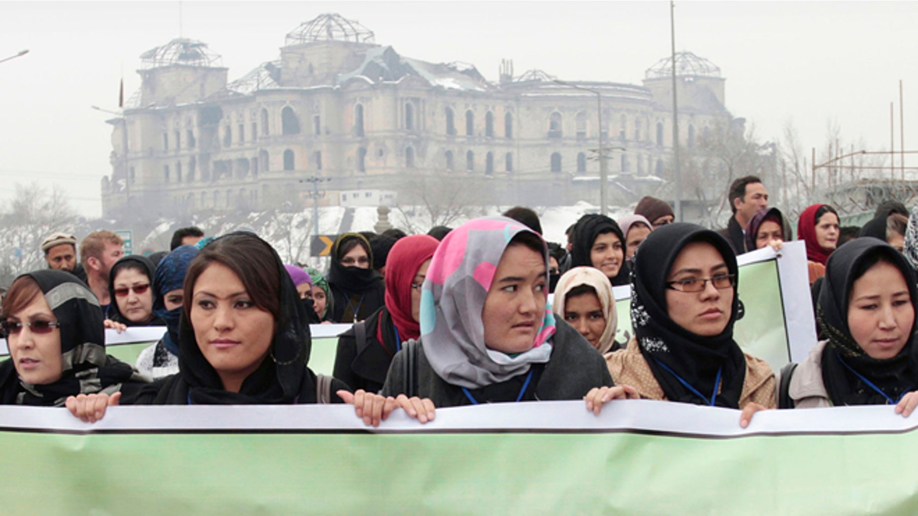 Feb. 14, 2013: Afghan women carry a banner during a march calling for end of violence against women, in Kabul, with the Darul Aman palace seen in the background, Afghanistan.