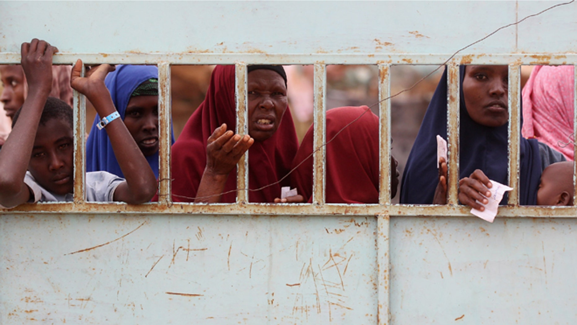 DADAAB, KENYA - JULY 23: Somalian refugees wait at the entrance to the registration area of the IFO refugee camp which makes up part of the giant Dadaab refugee settlement on July 23, 2011 in Dadaab, Kenya. The refugee camp at Dadaab, located close to the Kenyan border with Somalia, was originally designed in the early 1990s to accommodate 90,000 people but the UN estimates over 4 times as many reside there. The ongoing civil war in Somalia and the worst drought to affect the Horn of Africa in six decades has resulted in an estimated 12 million people whose lives are threatened. (Photo by Oli Scarff/Getty Images)