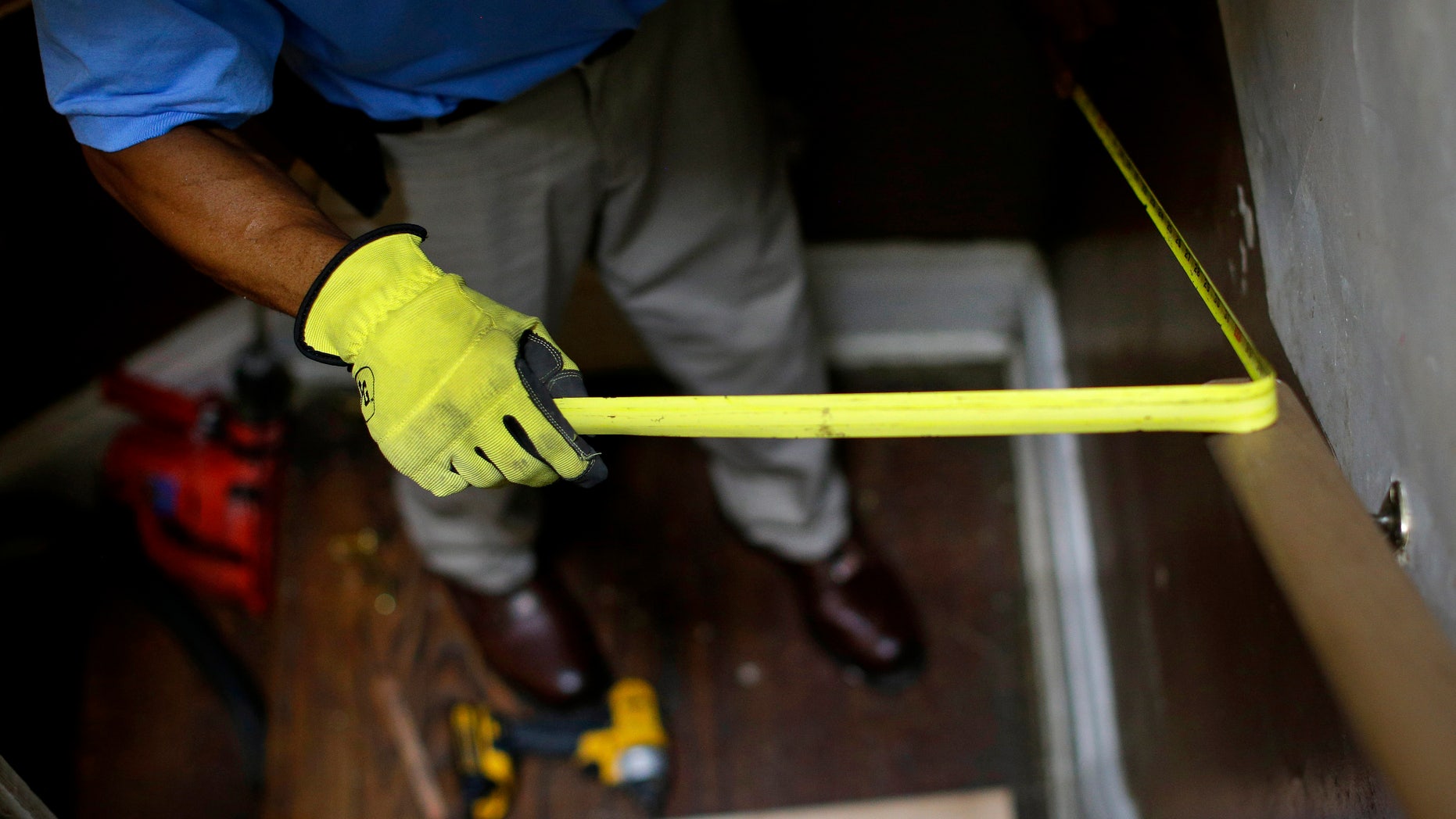 FILE - In this June 12, 2013 file photo, a construction worker takes a measurement while installing a banister in a staircase in a home in Baltimore. Where you live plays a big role in staying independent as you age. Now researchers say an innovative program that combined home fix-ups and visits from occupational therapists and nurses improved low-income seniors' ability to care for themselves in their own homes. (AP Photo/Patrick Semansky, File)